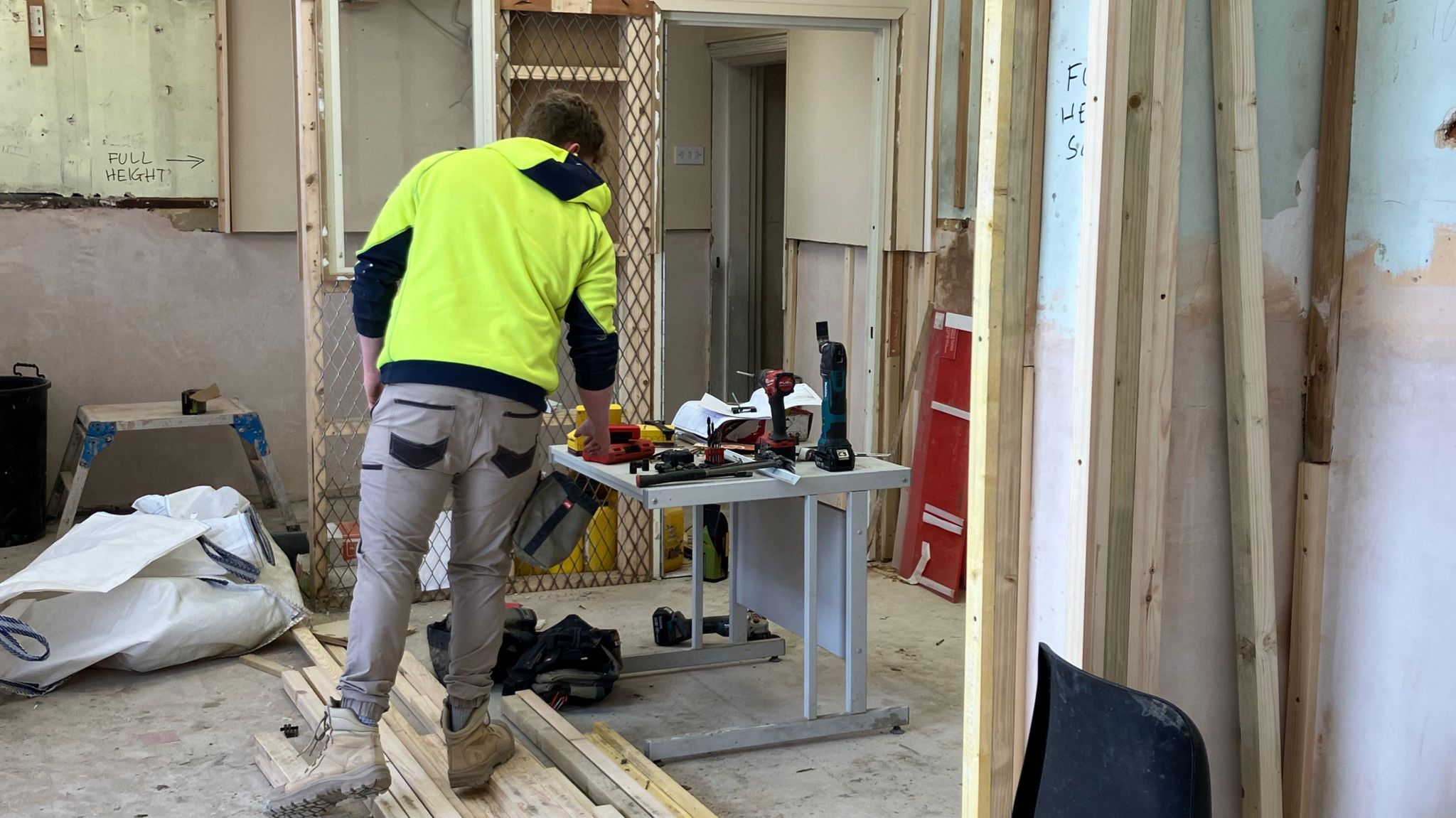 A builder in a fluorescent yellow jumper works inside the Post Office