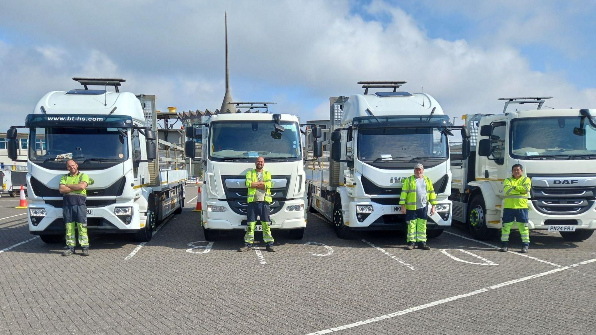 Four large white trucks with drivers stood in front
