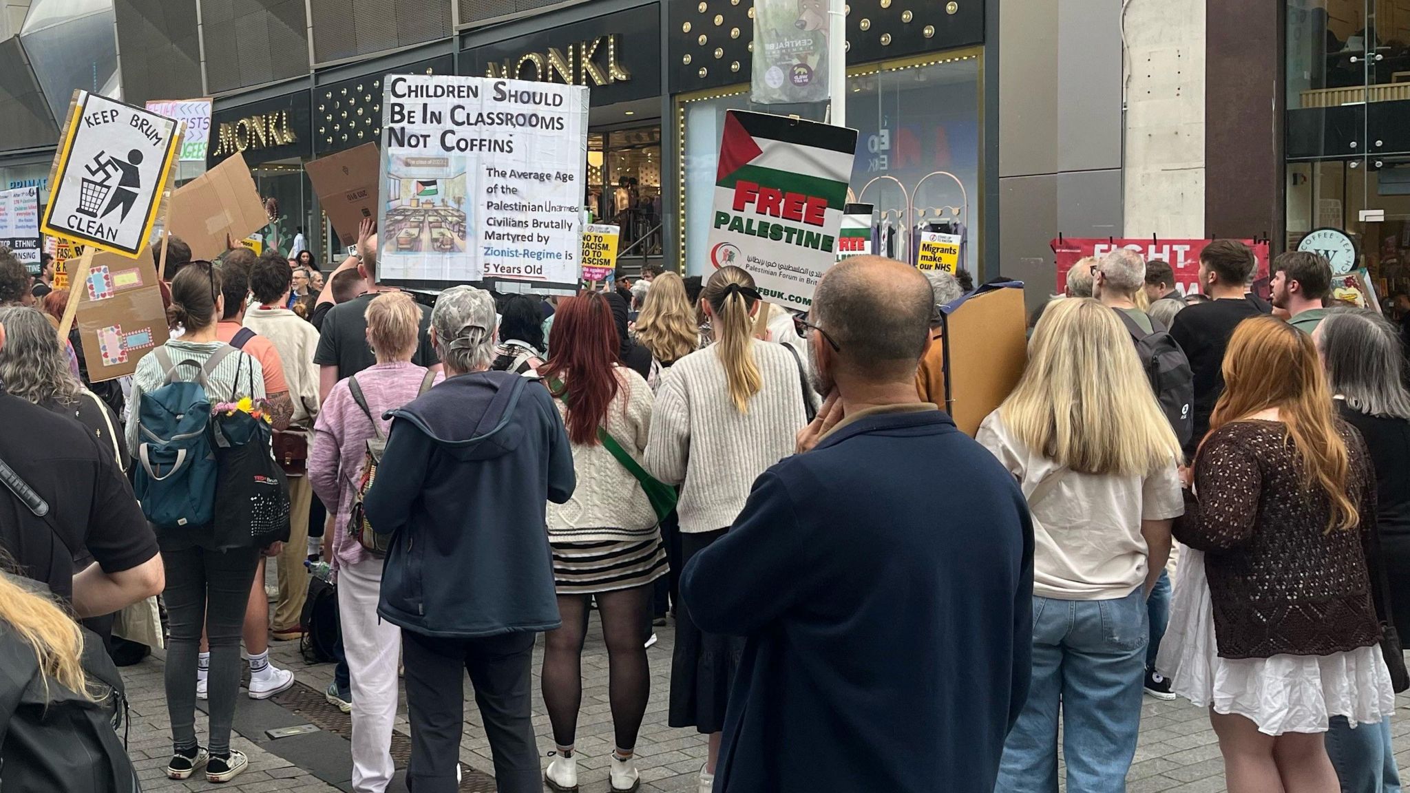 The back of a crowd holding protest signs