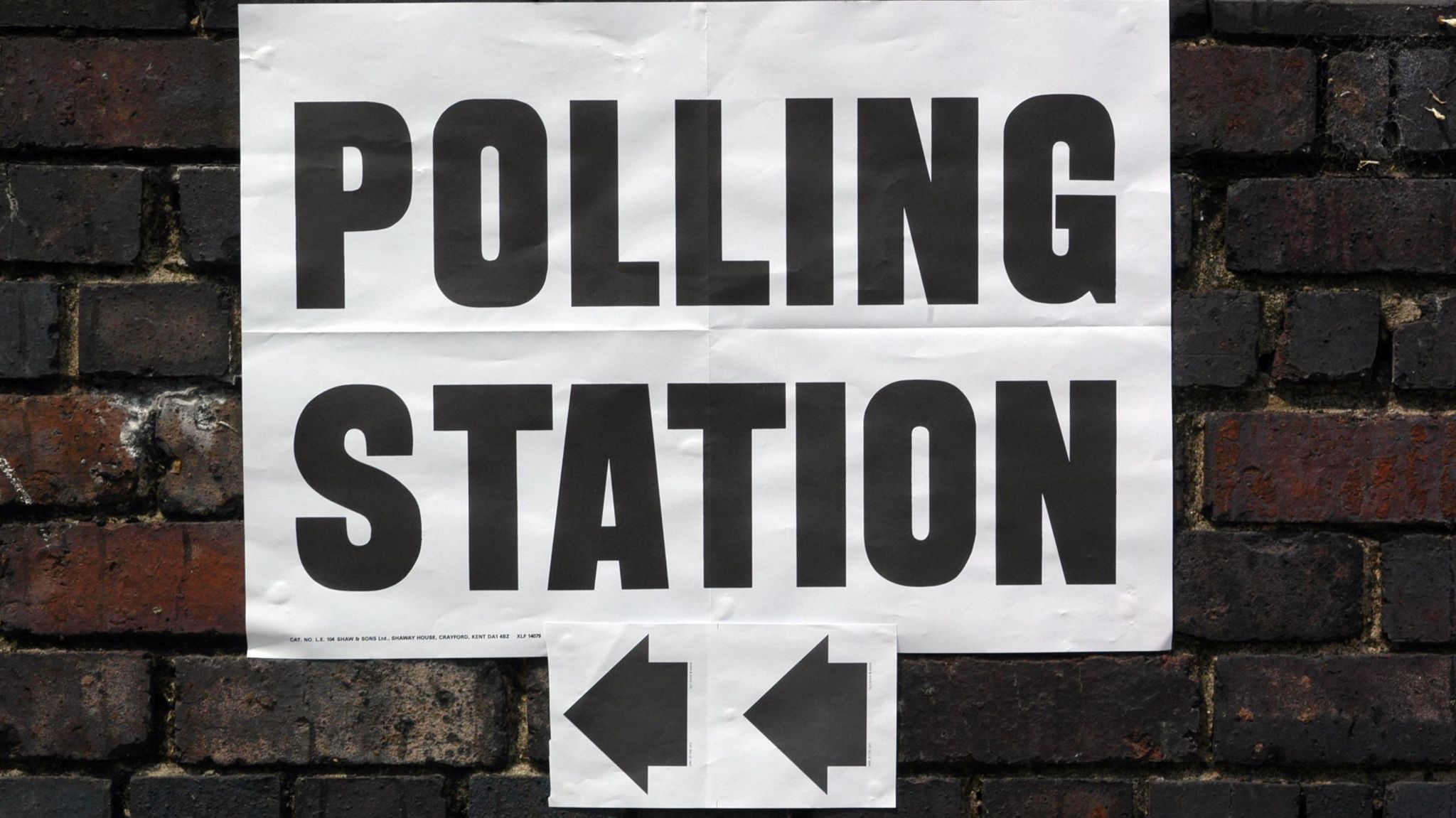 Polling station sign on brick wall