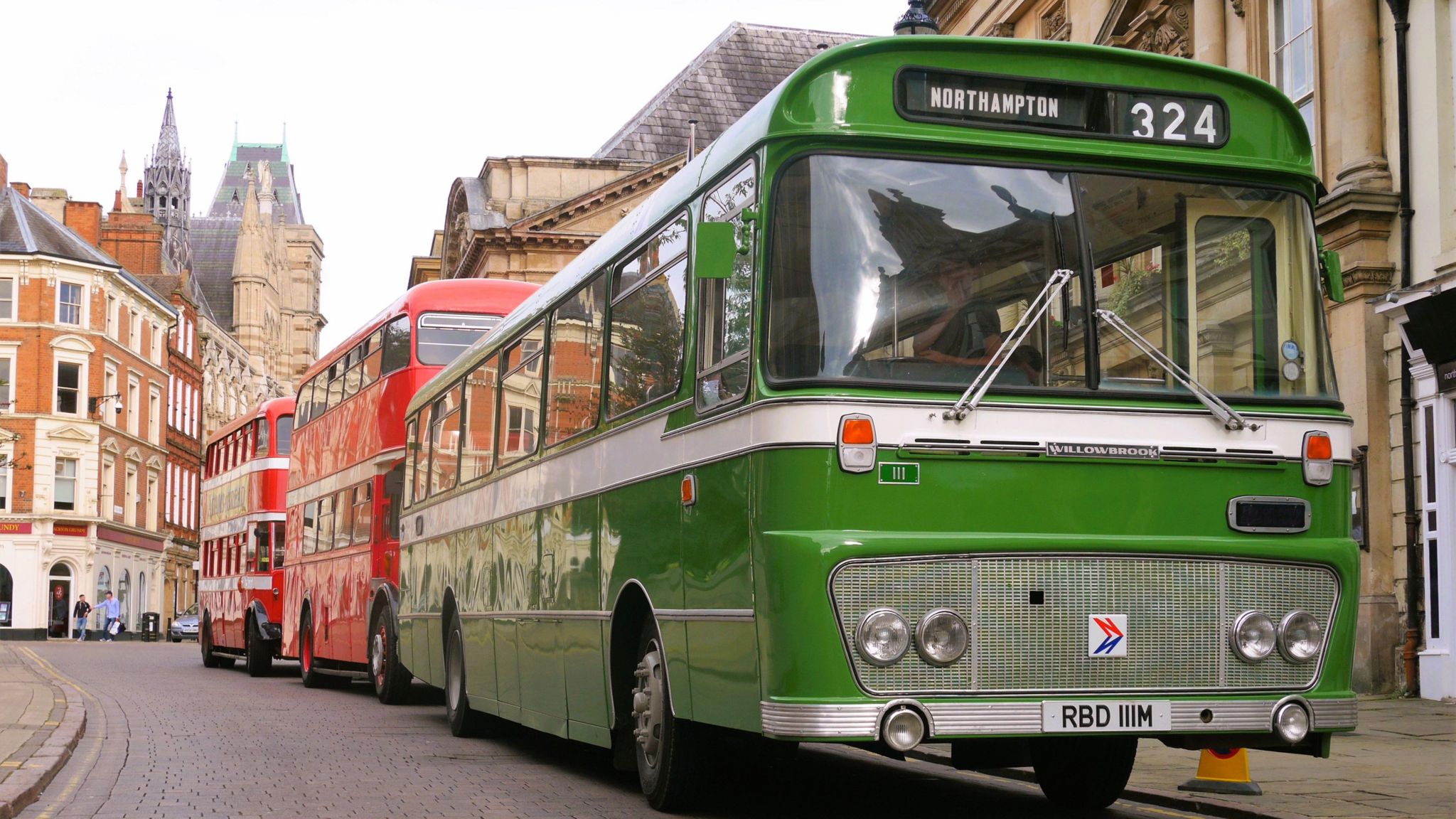 Green single-decker bus leading a line of buses