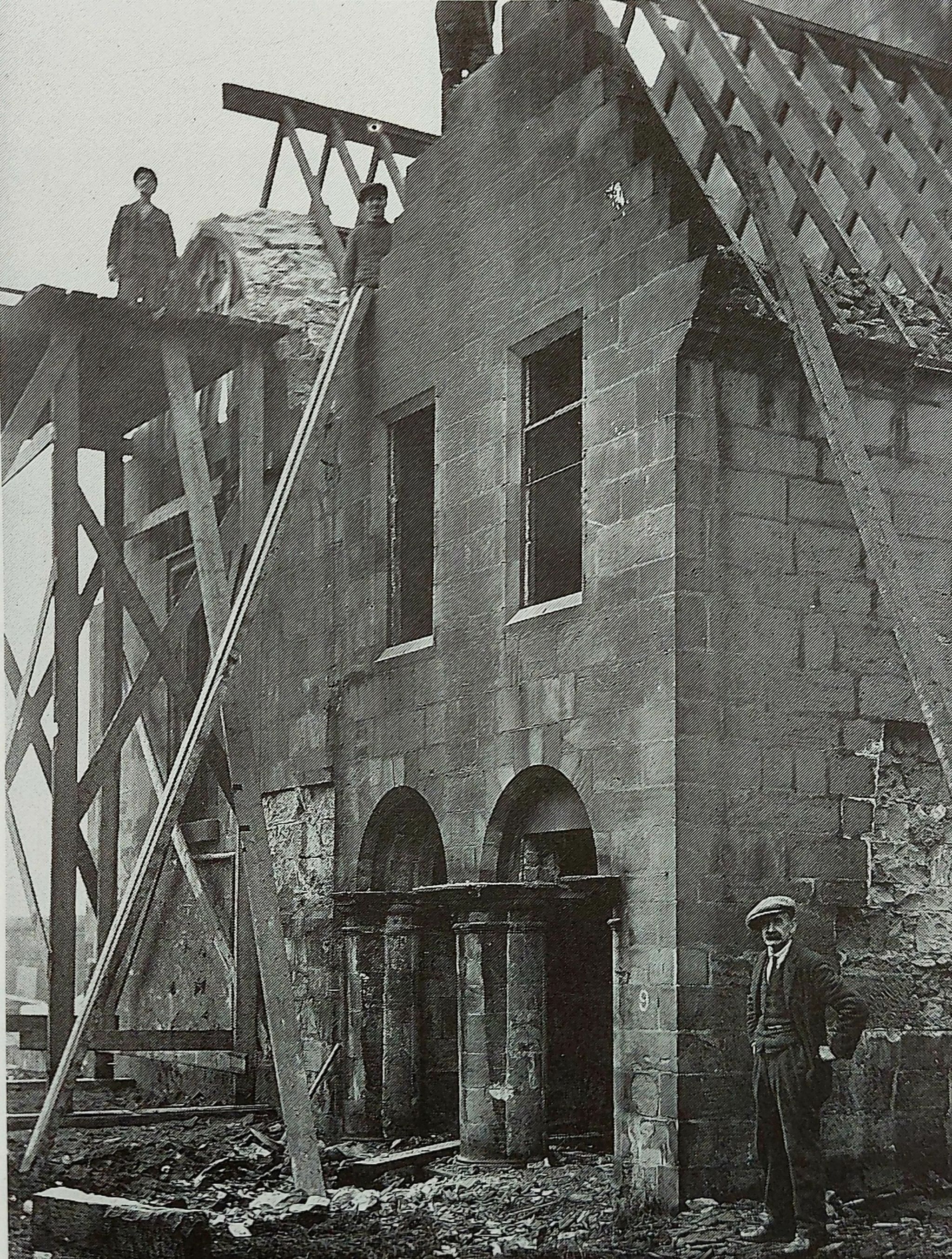Old West Kirk during deconstruction in the 1920s, missing a roof with workers standing observing