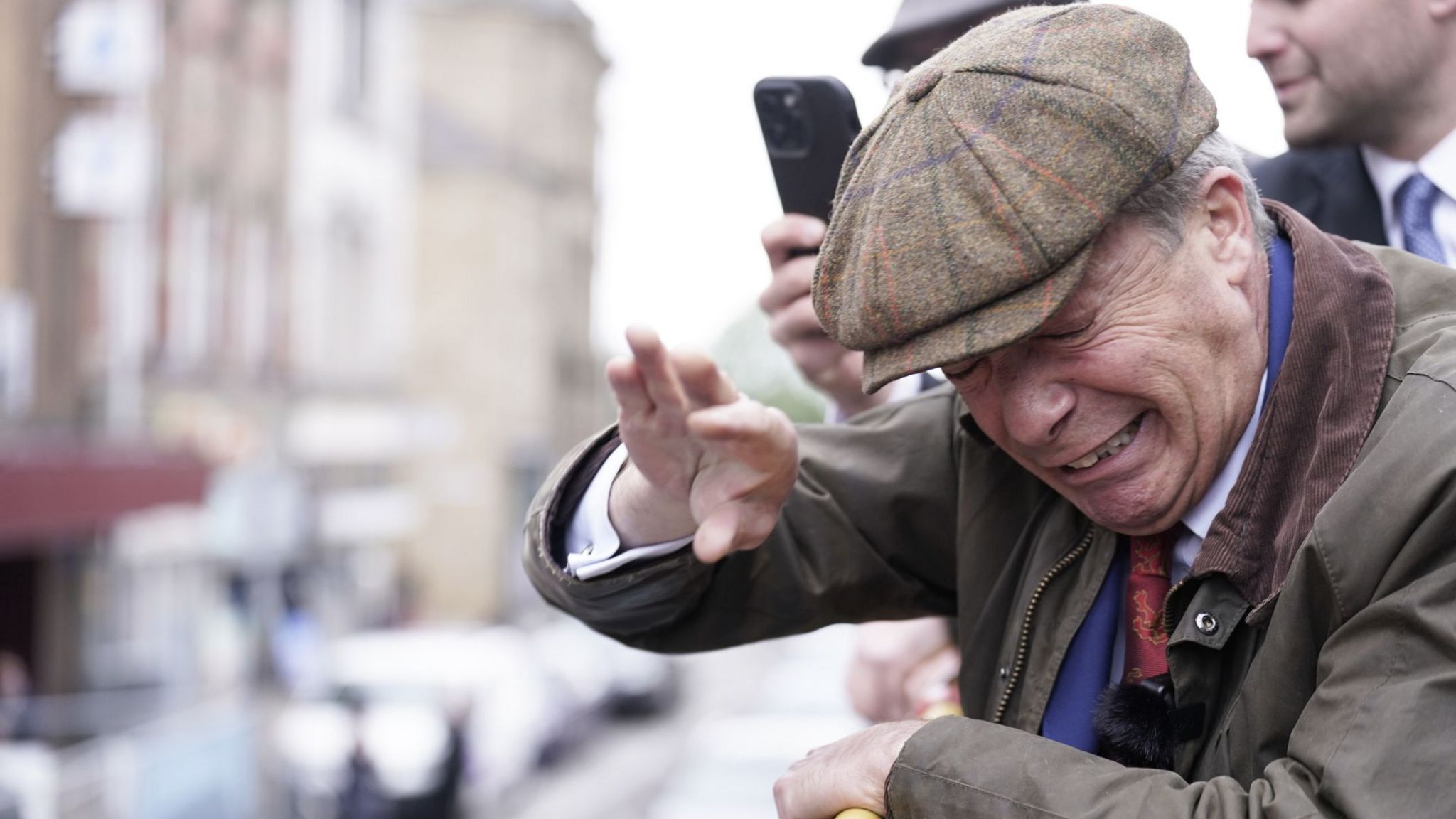 Nigel Farage holds his hand in front of his face