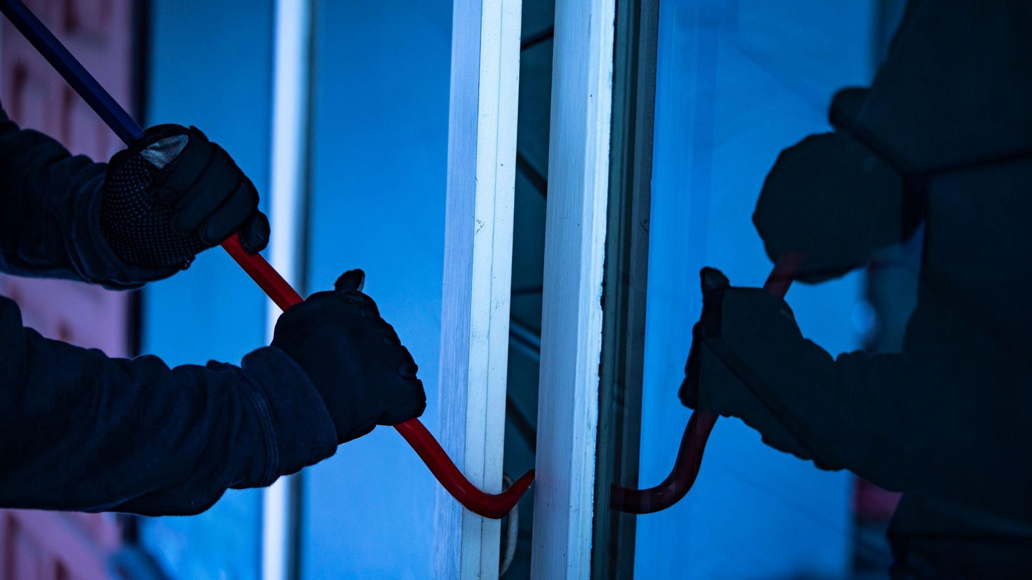 A man attempts to break into a house with a crowbar