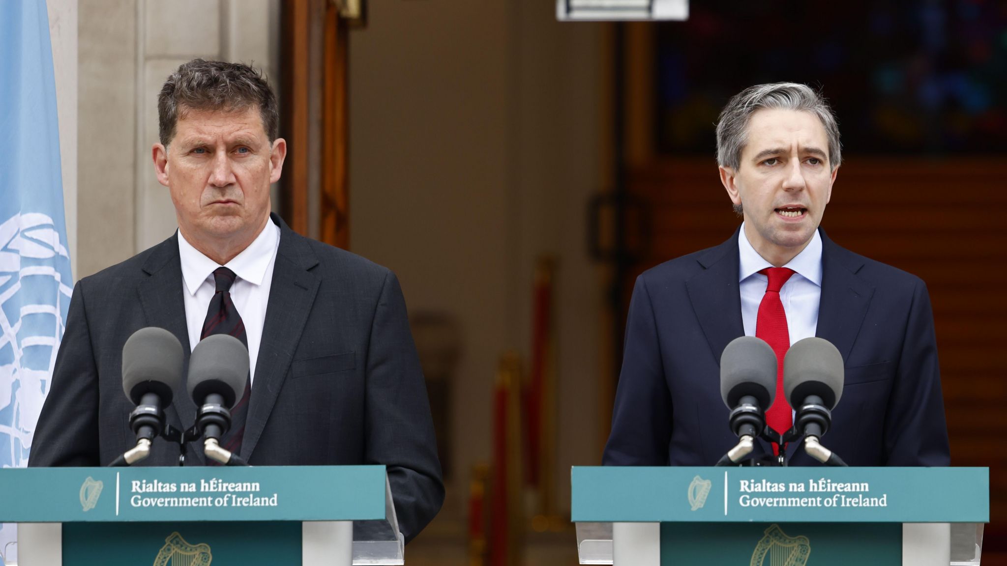 Eamon Ryan and Simon Harris standing behind podiums outside Government Buildings in Dublin