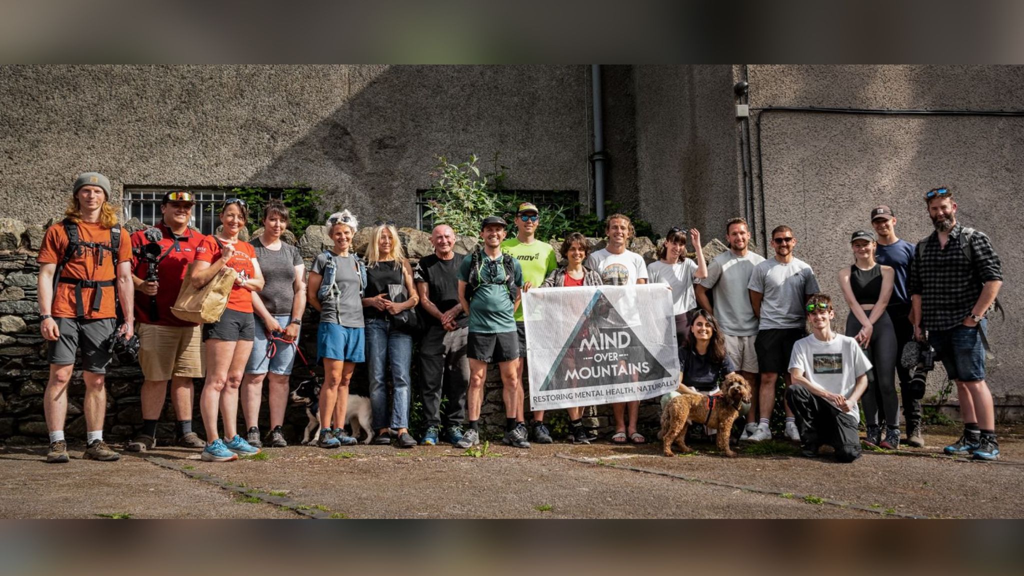 Image of a group of people. They are holding a white flag with the Mind Over Mountains logo on it.