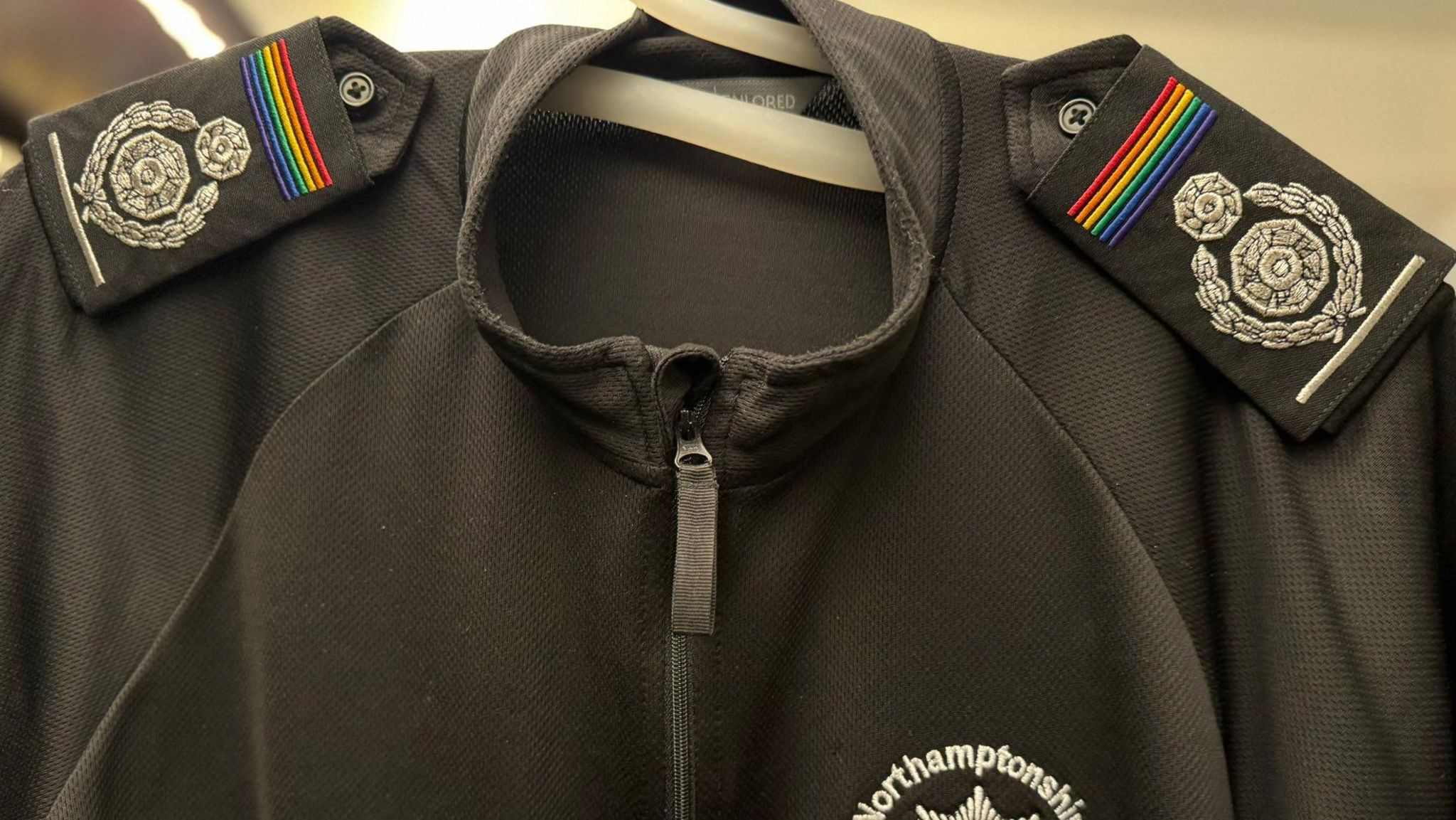 A shirt with Pride colours at the top of epaulettes.