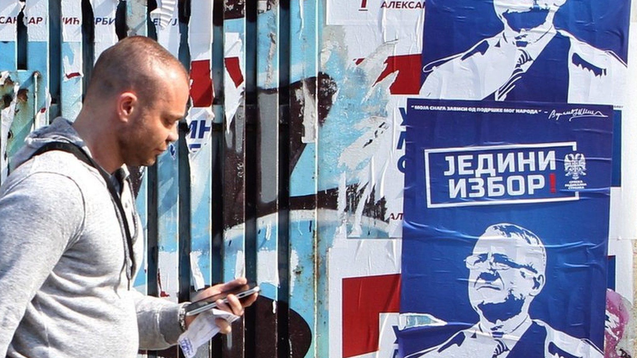A man walks past an election poster of Serbian Radical Party leader Vojislav Seselj in Belgrade, Serbia (23 April 2016)