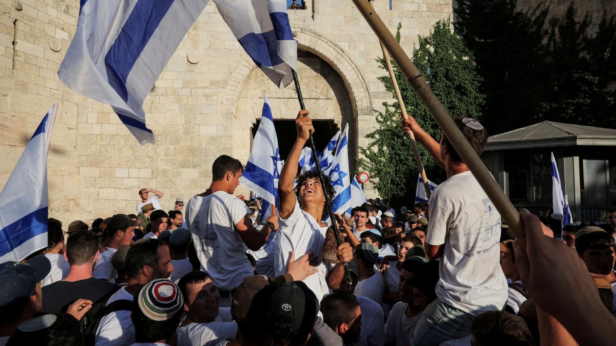 Young Israelis wave flags outside the entrance to the Muslim quarter of Jerusalem's Old City, in occupied East Jerusalem,at the start of the Jerusalem Day flag march (5 June 2024)