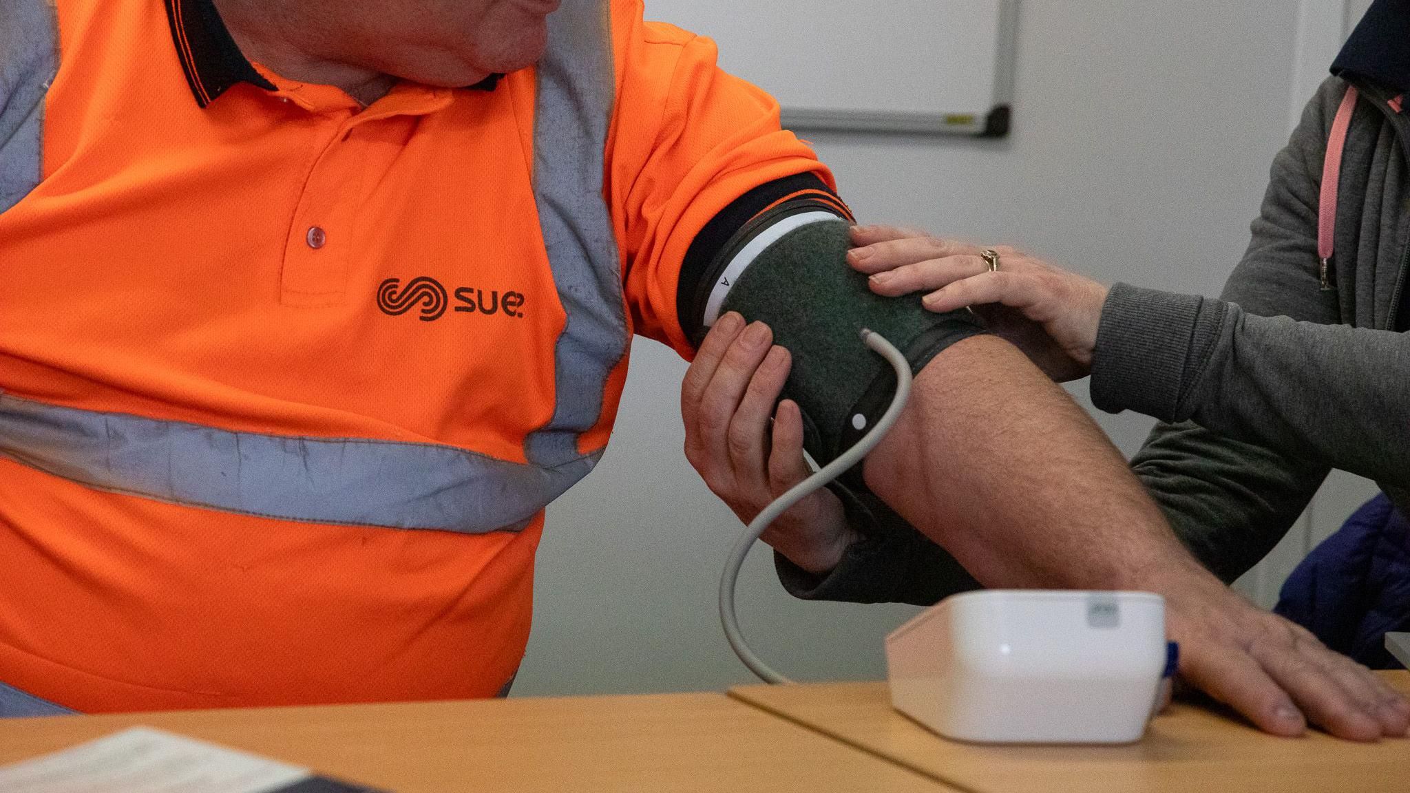 A man in a high vis jacket getting his blood pressure checked