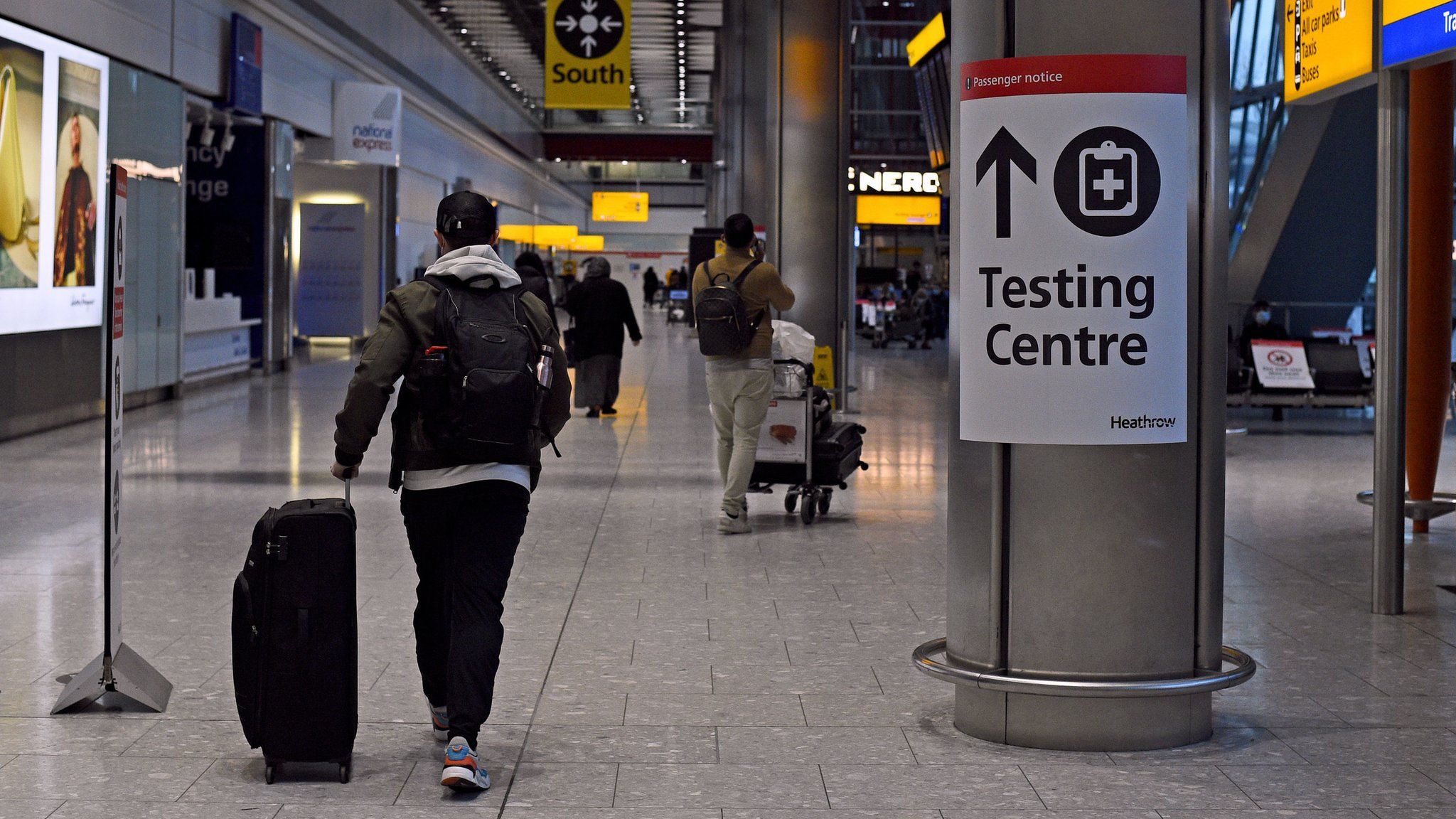 A passenger walks past a sign for the Covid testing centre at London's Heathrow Airport