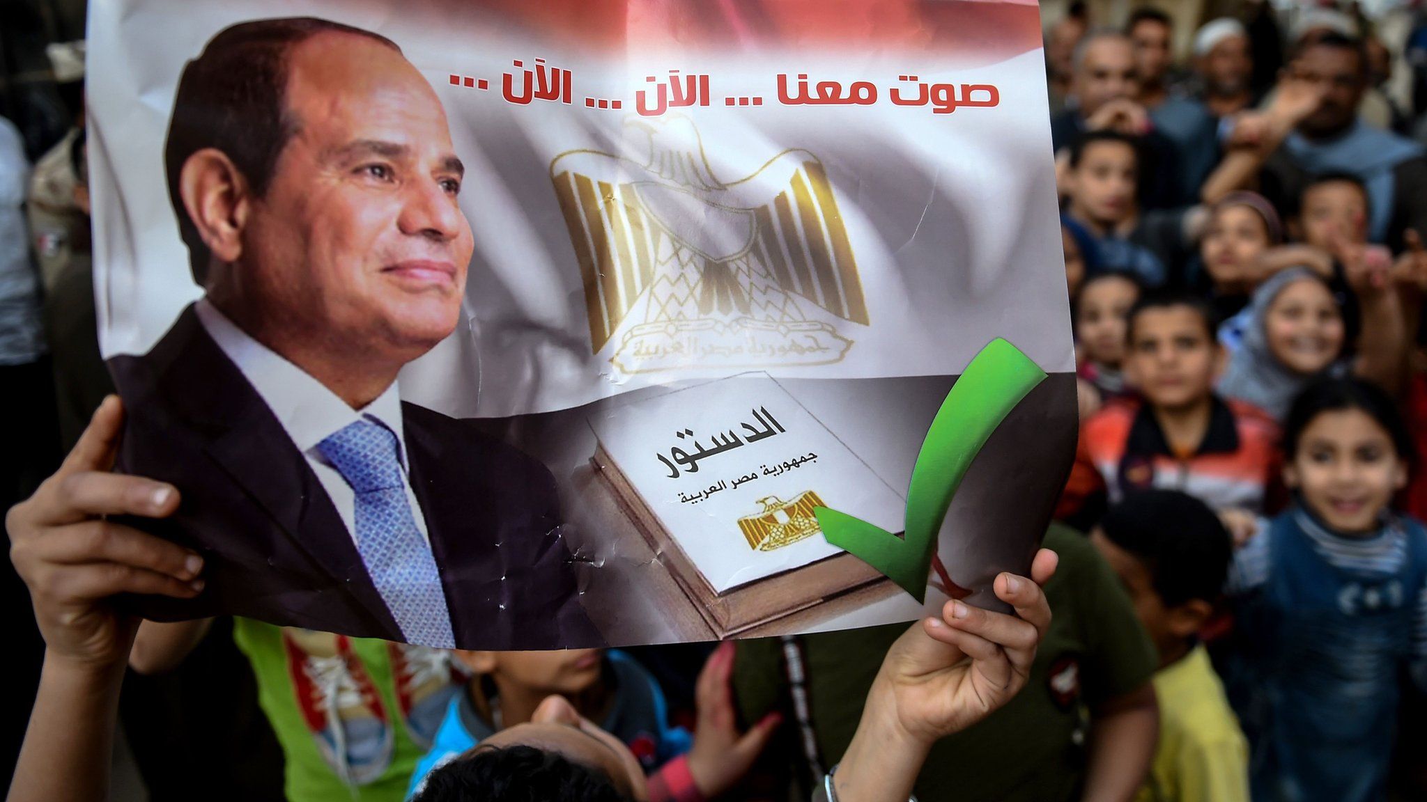 An Egyptian man holds up a banner saying: "Vote with us... now... now" at a polling station in Menoufia (22 April 2019)