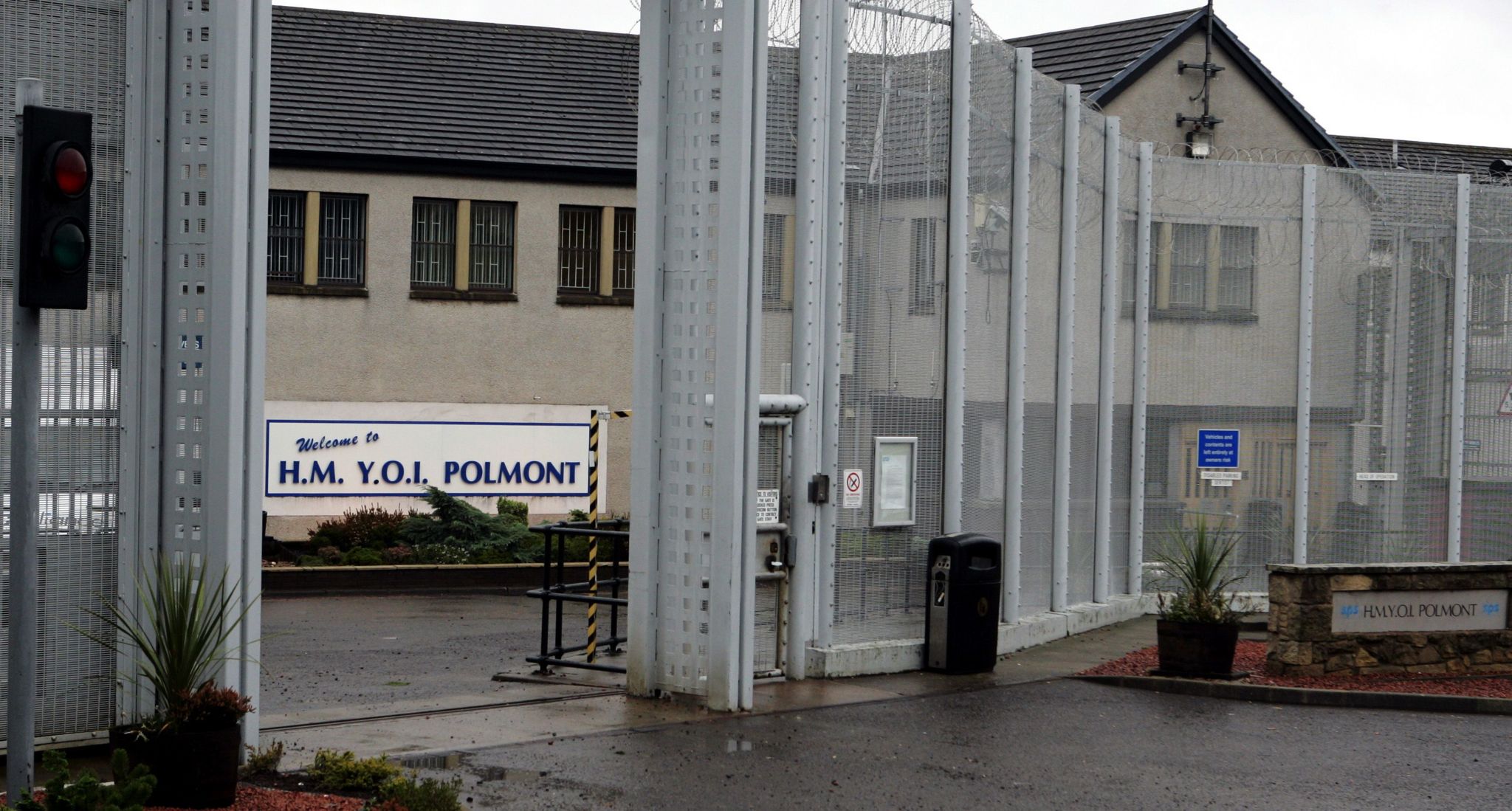 Exterior shot of HM YOI Polmont - a sand coloured building surrounded by wire fencing and bars on the windows