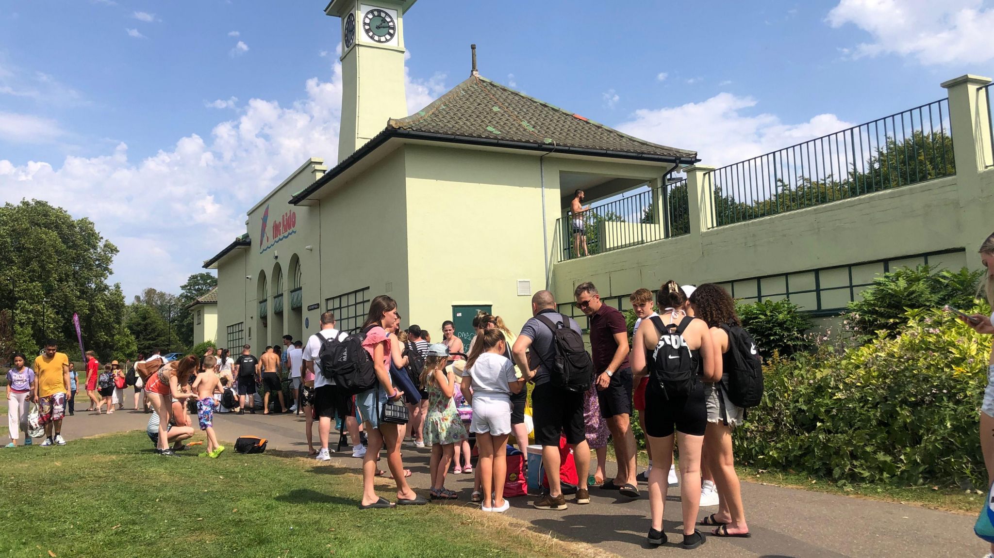  A queue of men, women and children outside a 1930s Lido on a hot summer's day