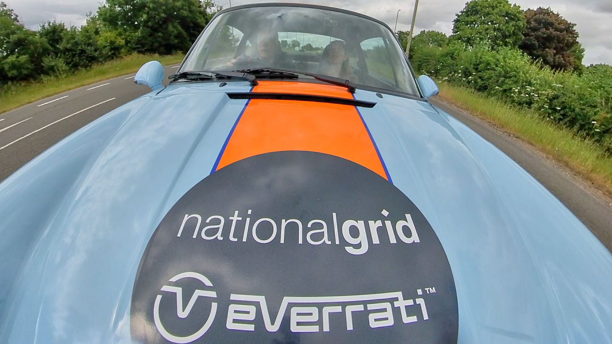 View through the windscreen of BBC transport Paul Clifton driving a classic Porsche sports car. His adult daughter Frankie is in the passenger seat.