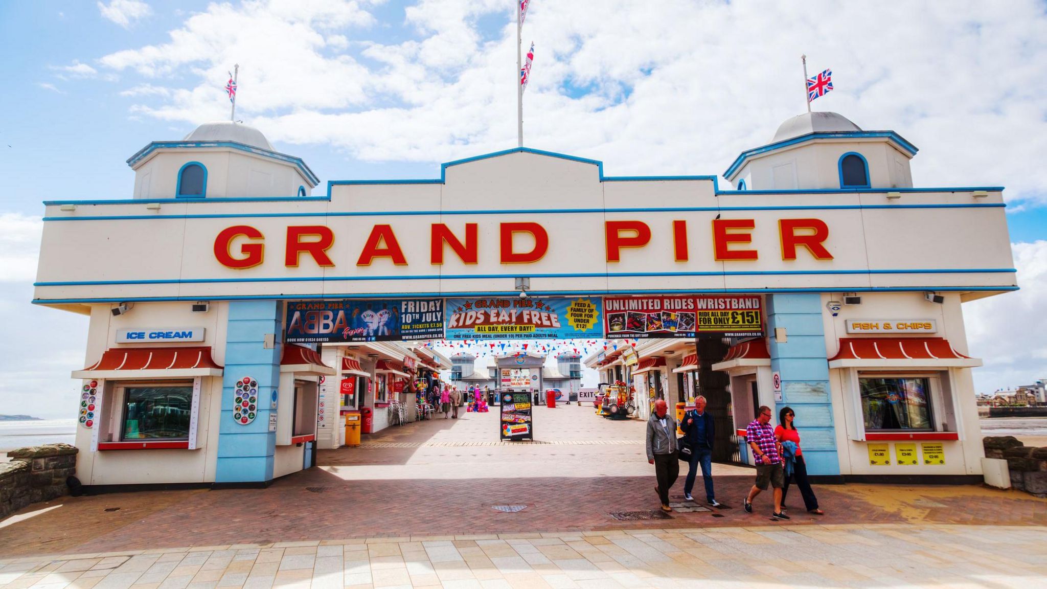 The Grand Pier entrance with people walking out and the sea in the background