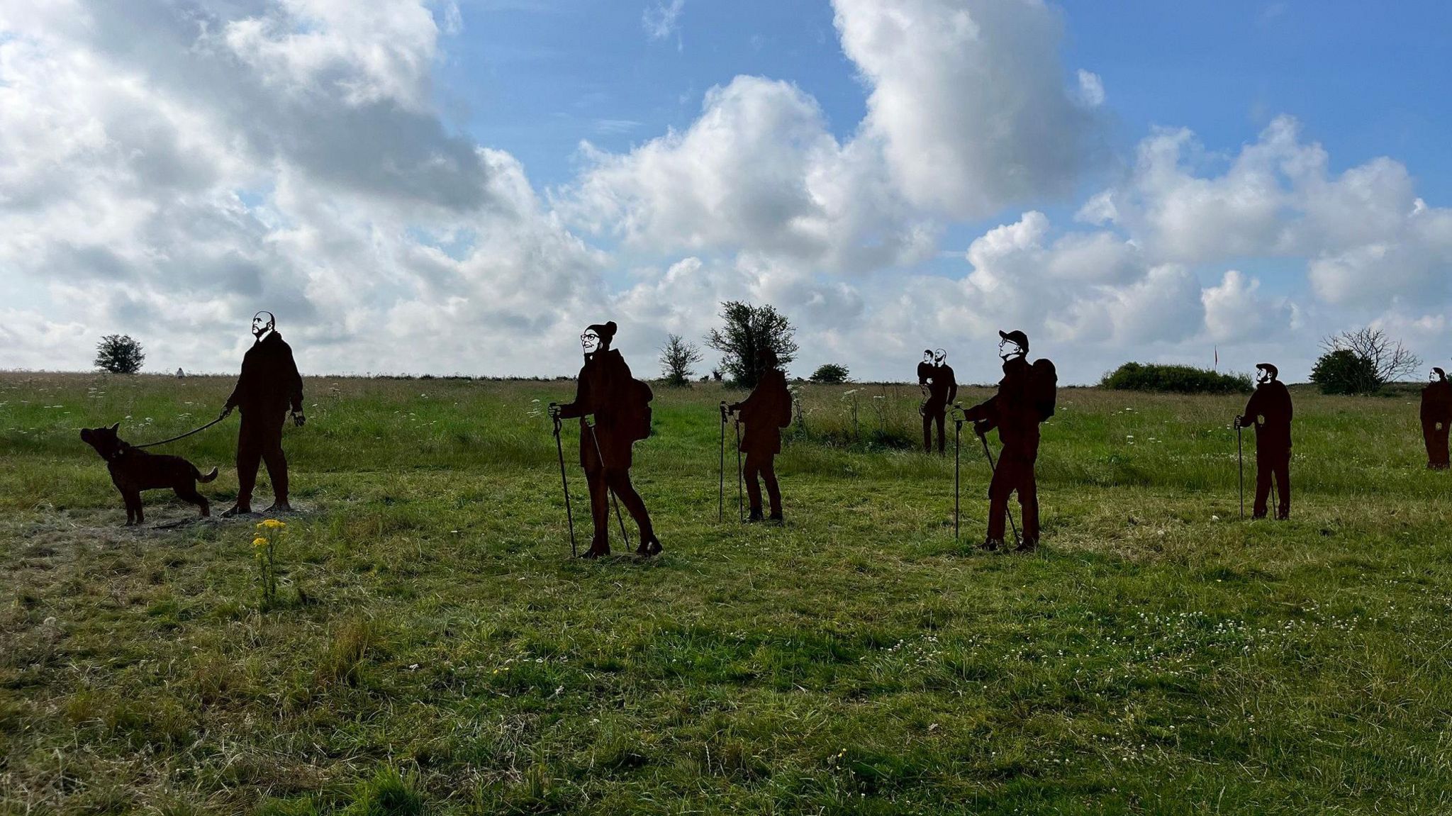 Statues representing members of the public who might want to walk on the land. One has a dog, and others have walking poles