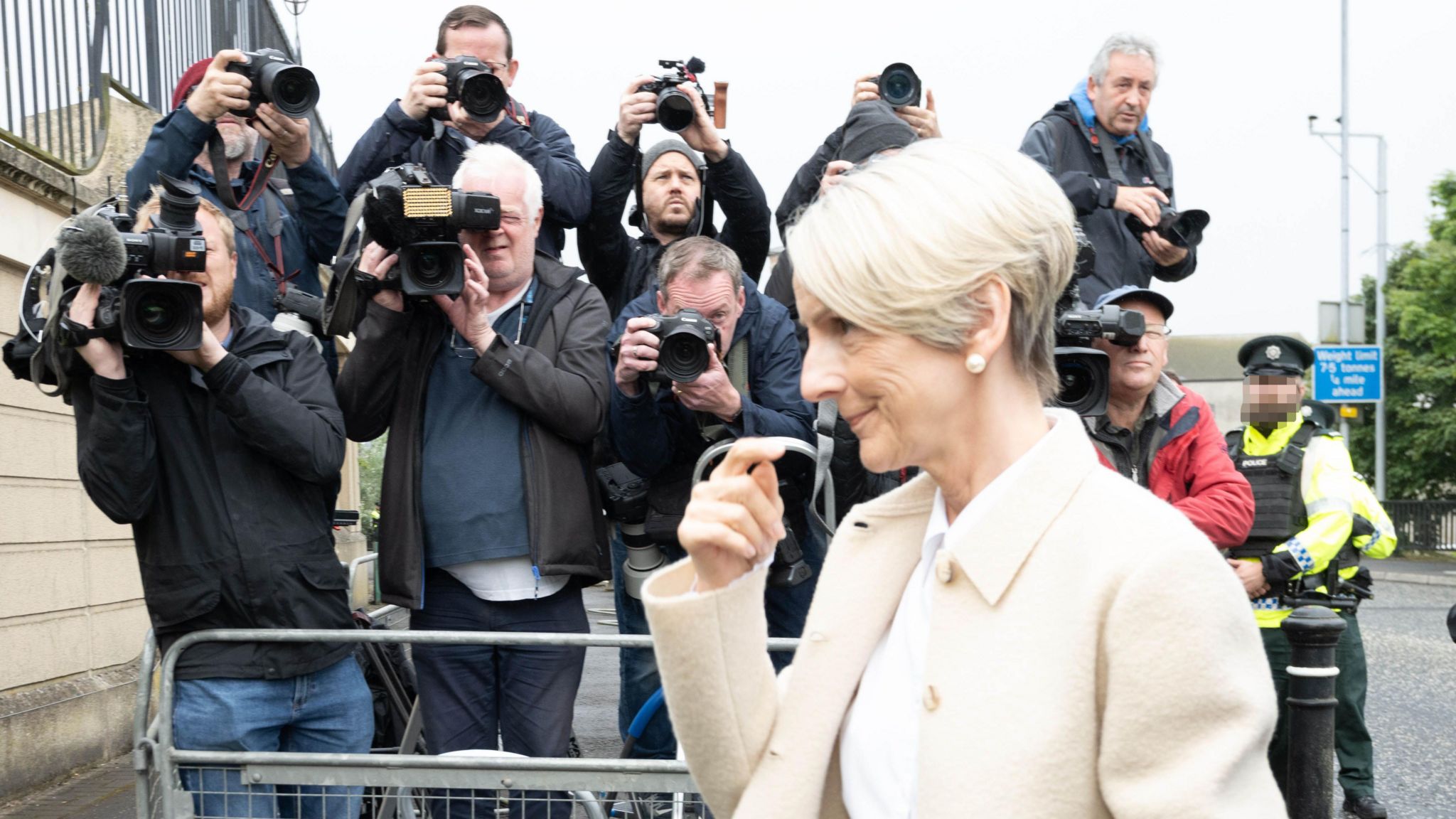 Lady Eleanor Donaldson wearing a cream blazer walks members of the media