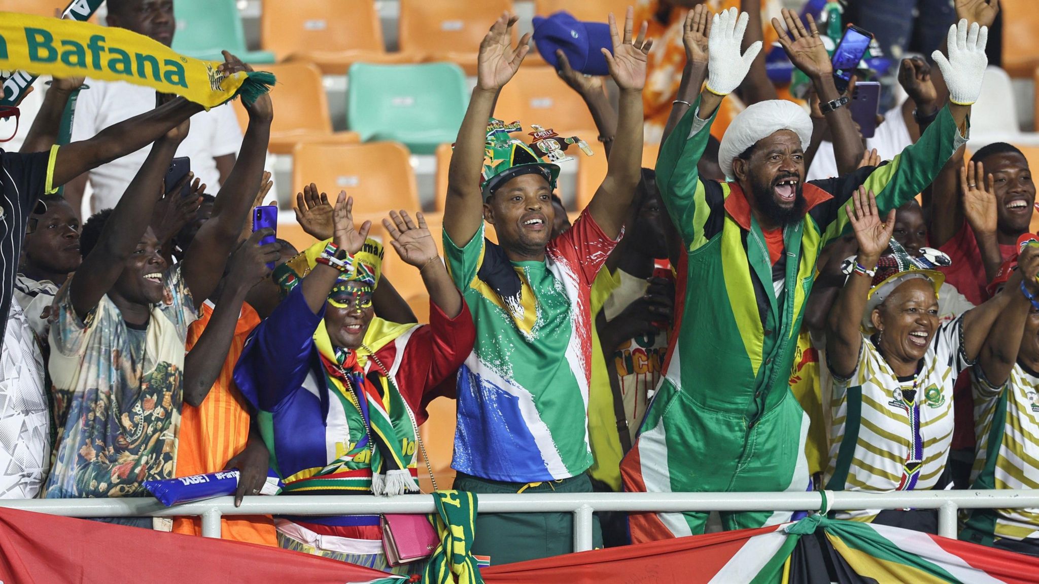 A group of South African superfans wave from the stands 