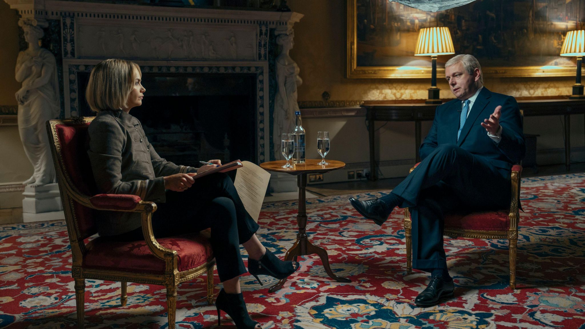 A man and woman sit facing each other at a small table, engaging in an interview.