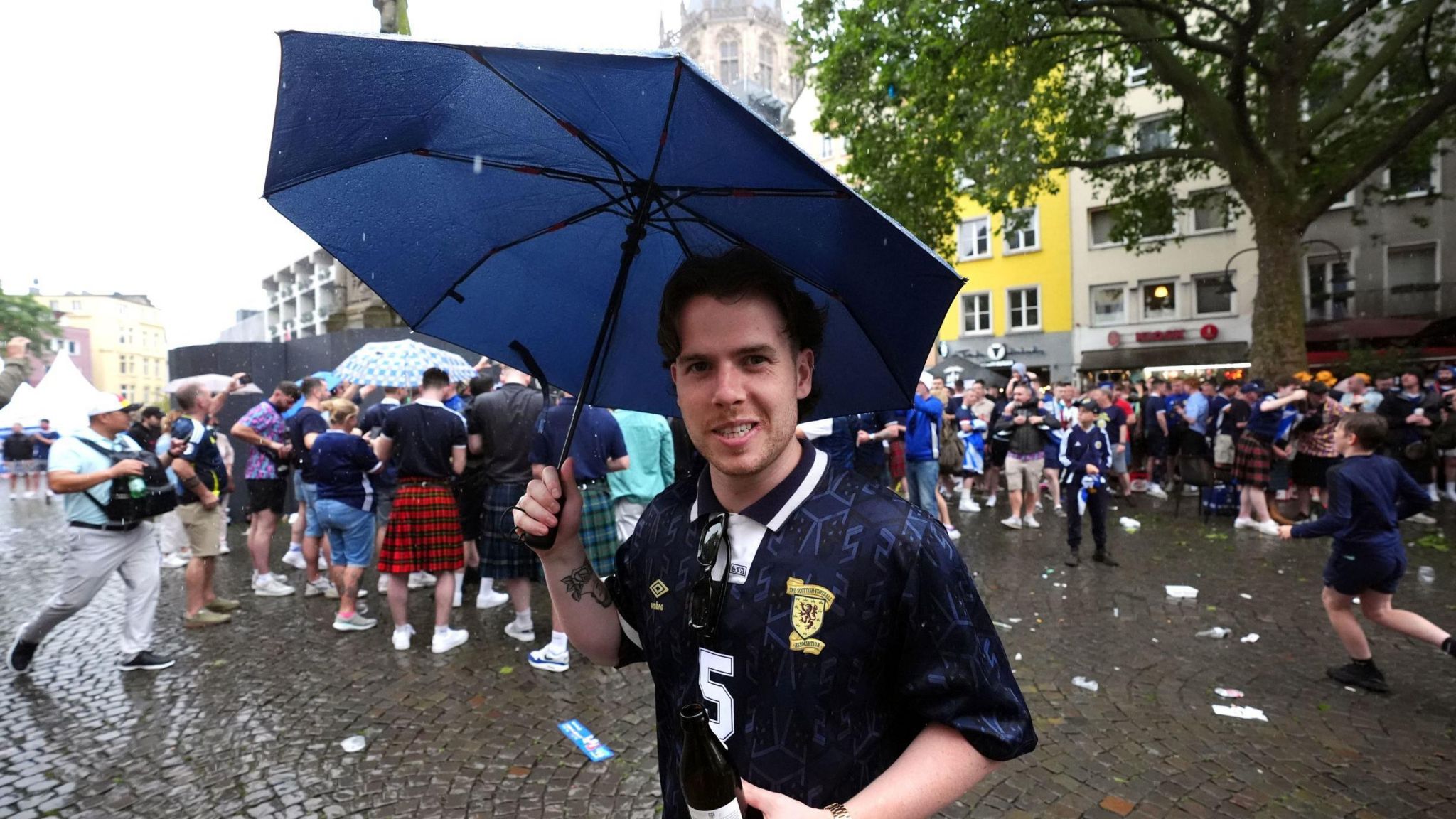 A Scotland fan holds an umbrella in Cologne during heavy rain