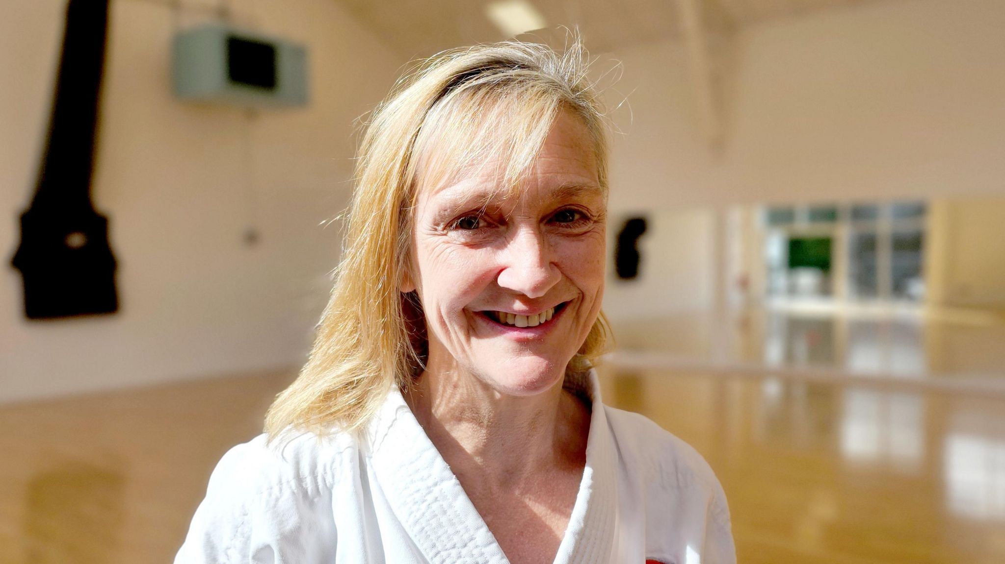 Karate instructor Joanne Minnis, smiling in the dojo where she teaches