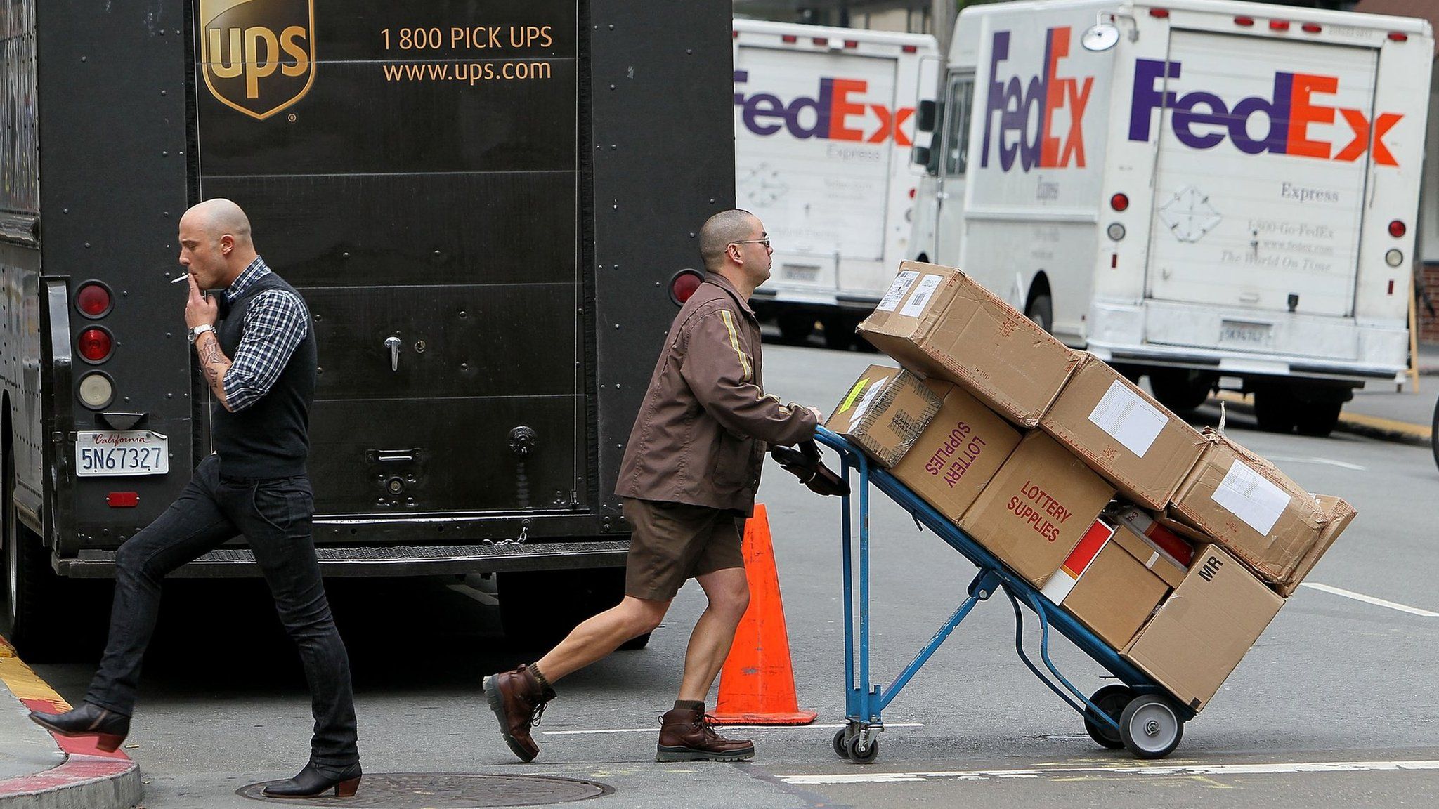 United Parcel Service (UPS) driver Grant Jung (R) pushes a handtruck loaded with boxes as he makes deliveries in San Francisco,
