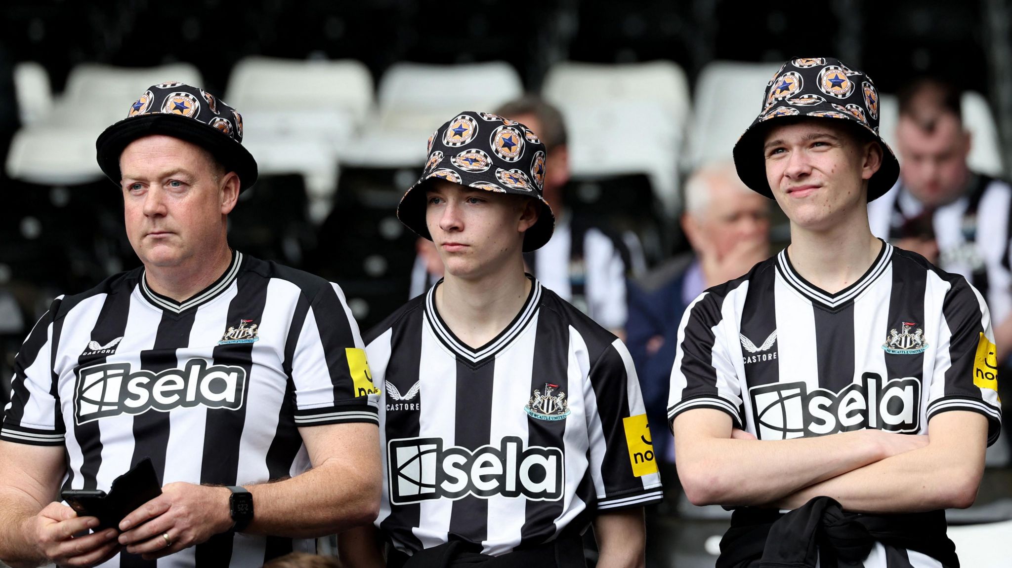 Three fans with flowery hats and Newcastle hats