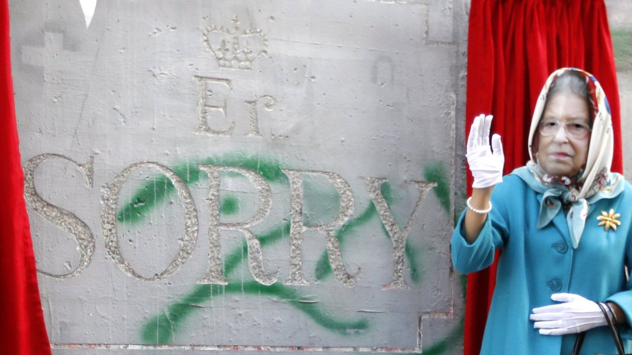 An actor dressed as Queen Elizabeth II unveils a mock apology for the Balfour Declaration etched into Israel's West Bank barrier that says: "Er... Sorry."
