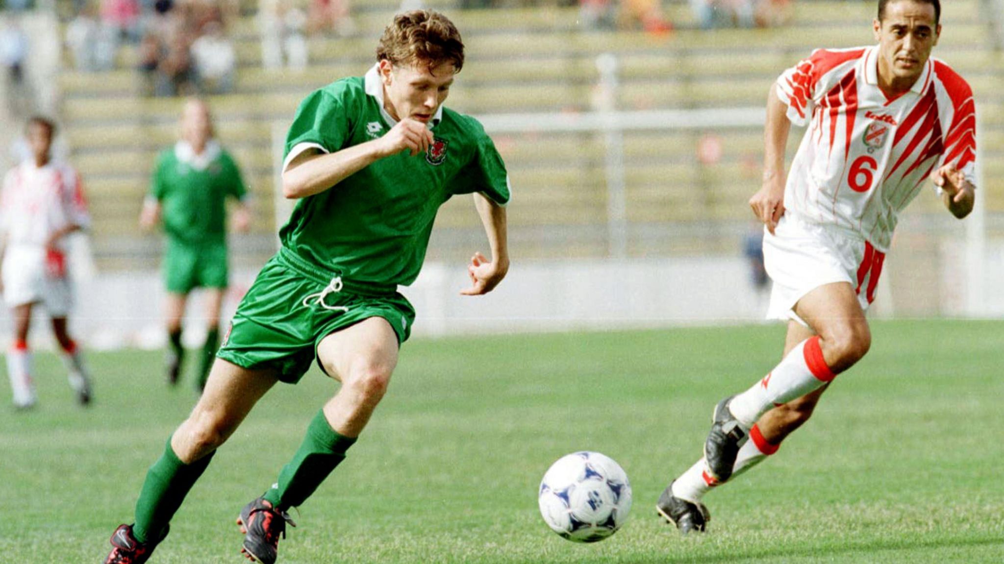 Wearing a green away shirt, Craig Bellamy of Wales breaks away from Ferid Chouchan