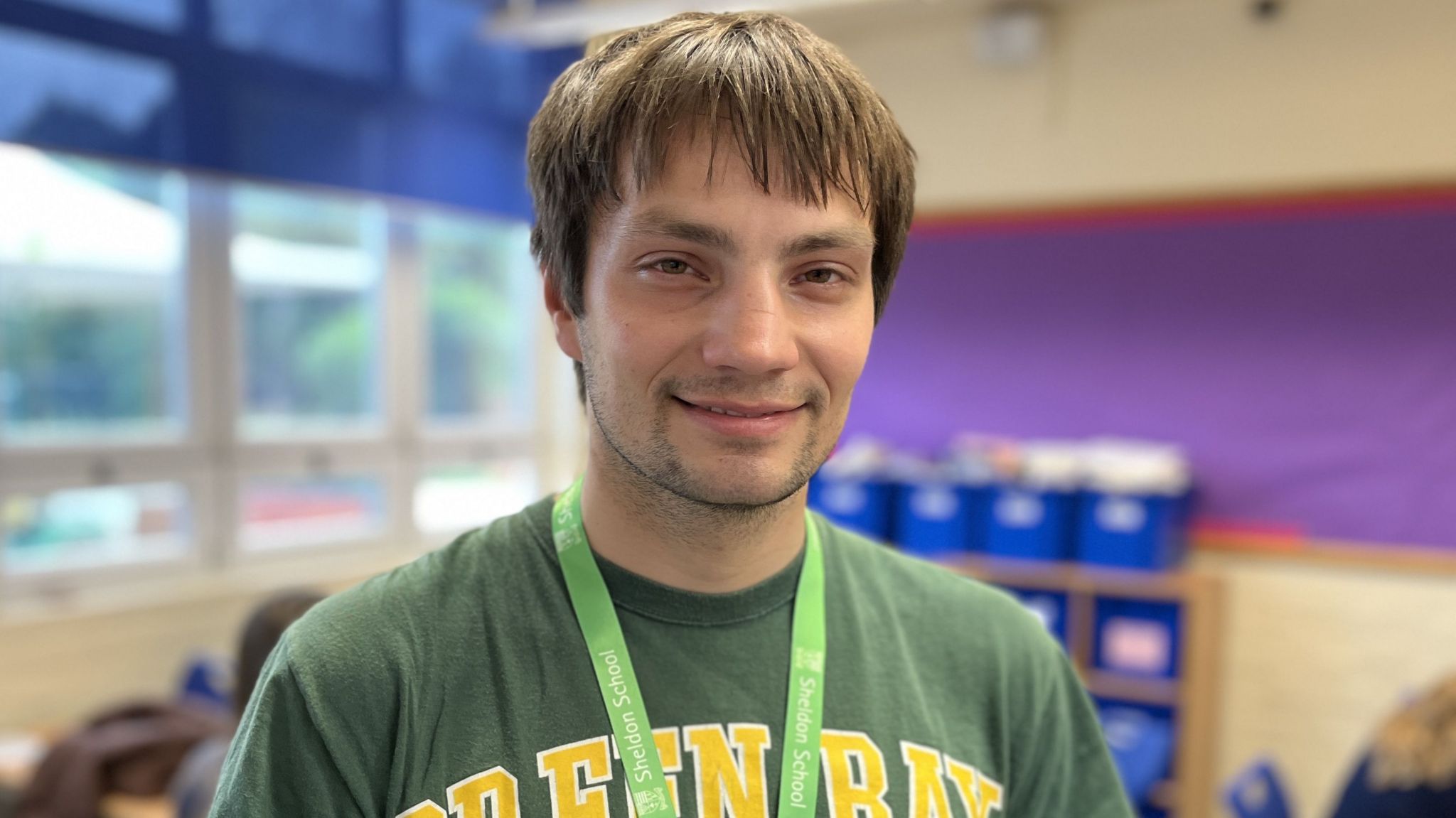 Former student, Kieran Pidgeon, smiling with short brown hair wearing a green t-shirt