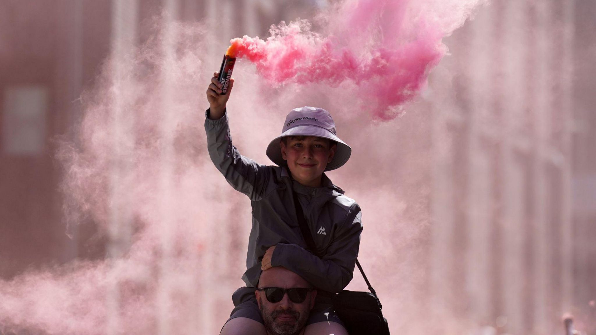 A young fan holding a smoke flare makes their towards Wembley Stadium
