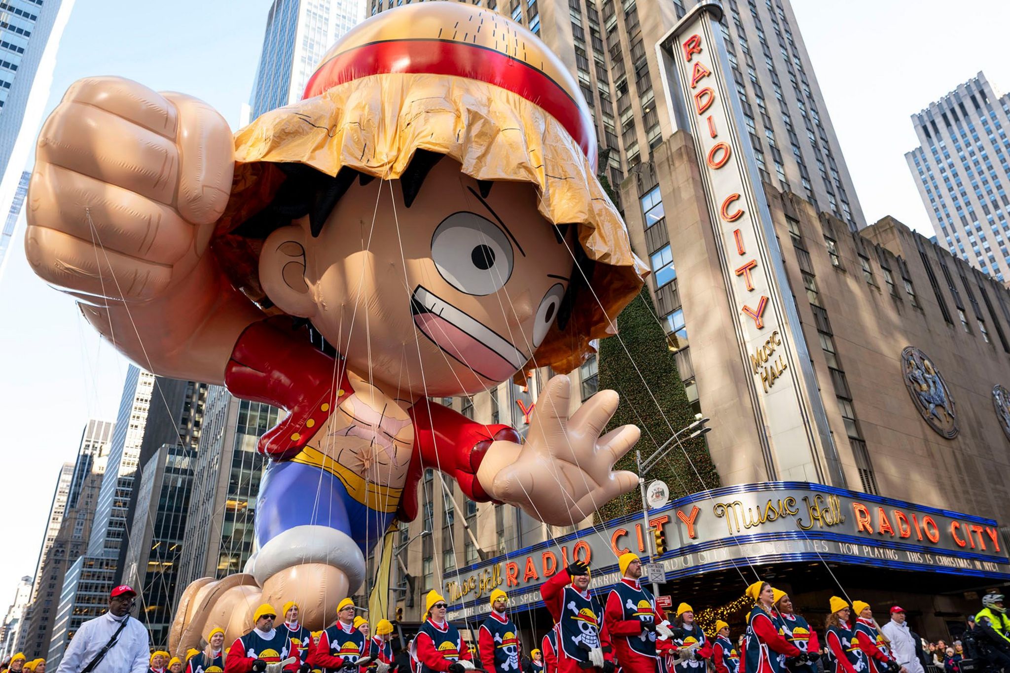 a giant balloon in the shape of one piece character monkey d luffy outside of radio city music hall in new york city