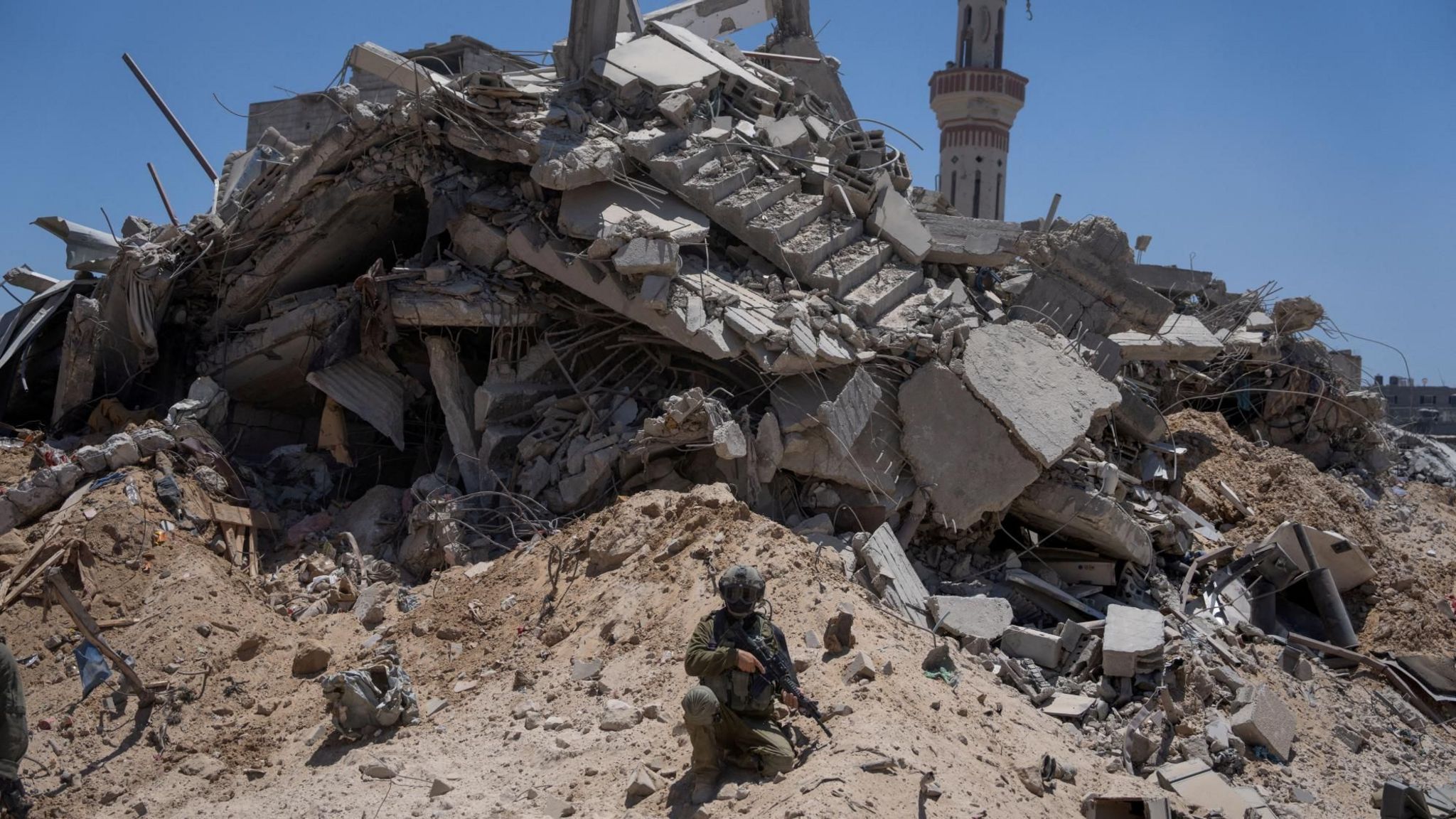 Israeli soldier sits next to a destroyed building in Rafah, in the southern Gaza Strip, during a tour for reporters (3 July 2024) 