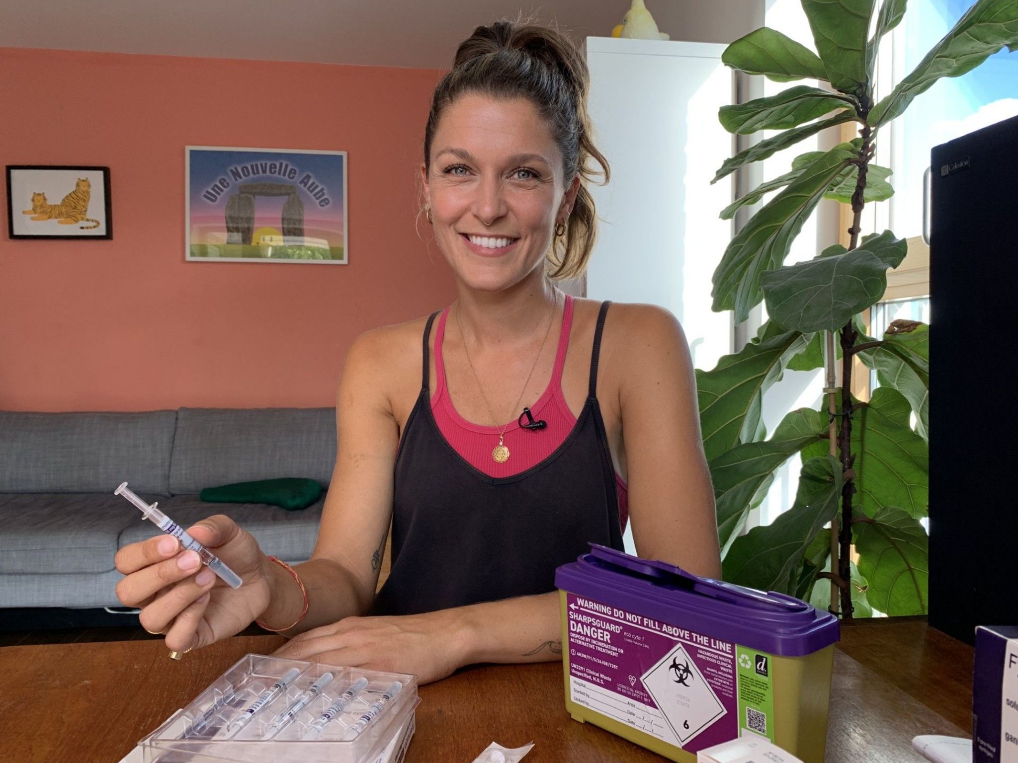 Egg Donor Charlotte Holmes smiles while holding a hormone injection in her living room