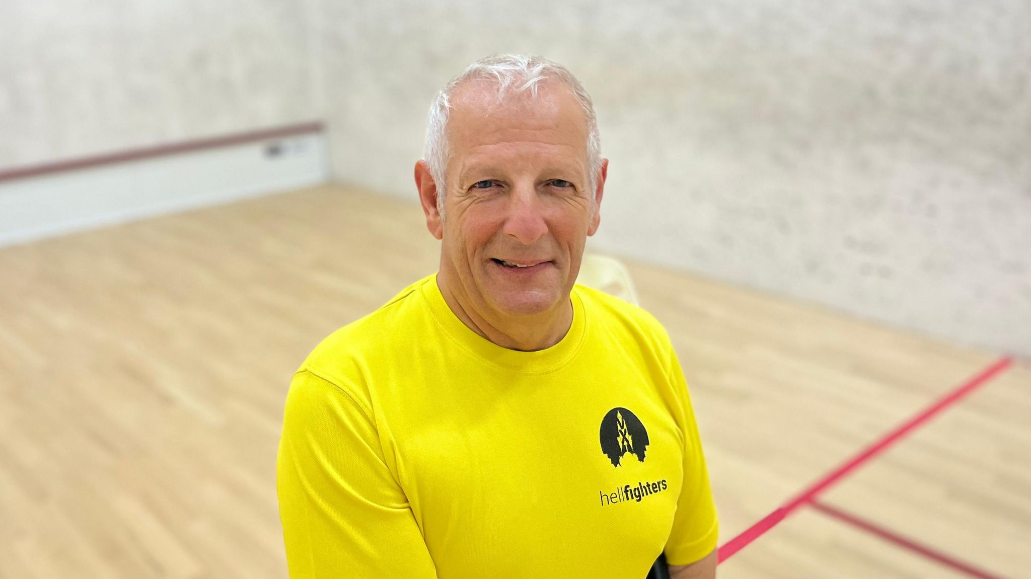 Paul Hildreth on the squash court wearing a bright yellow shirt 