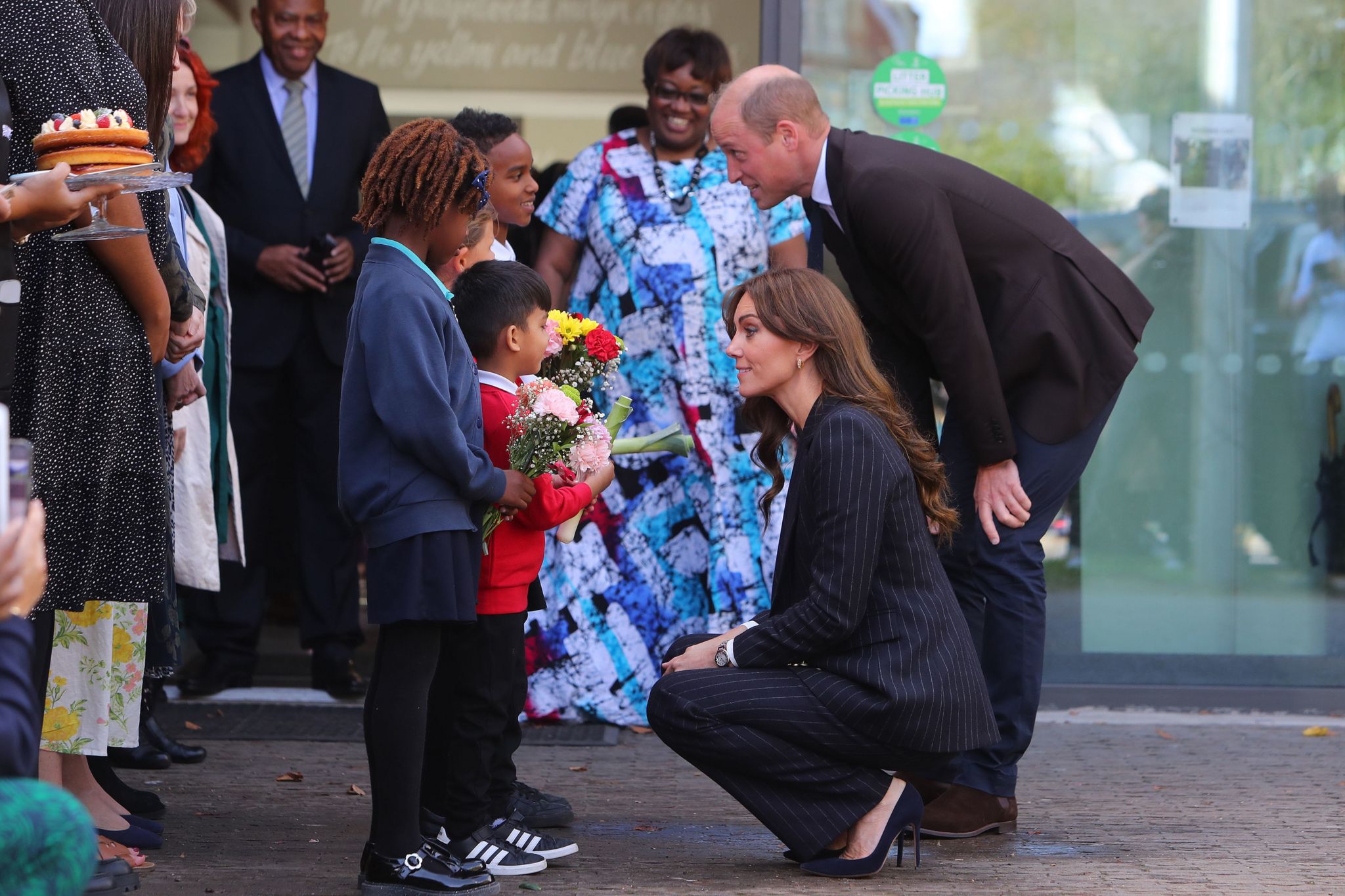 The Prince and Princess of Wales receive flowers from Akachi, 6, Humzah, 6, Ayla-May, 7, and Mazin, 8 after a visit to the Grange Pavilion in Cardiff to meet with members from the Windrush Cymru Elders, Black History Cymru 365, and the Ethnic Minority Youth Forum for Wales, and hear about the contribution the Windrush generation has had on the Welsh community and learn about how young minority ethnic individuals are creating positive change in Wales.