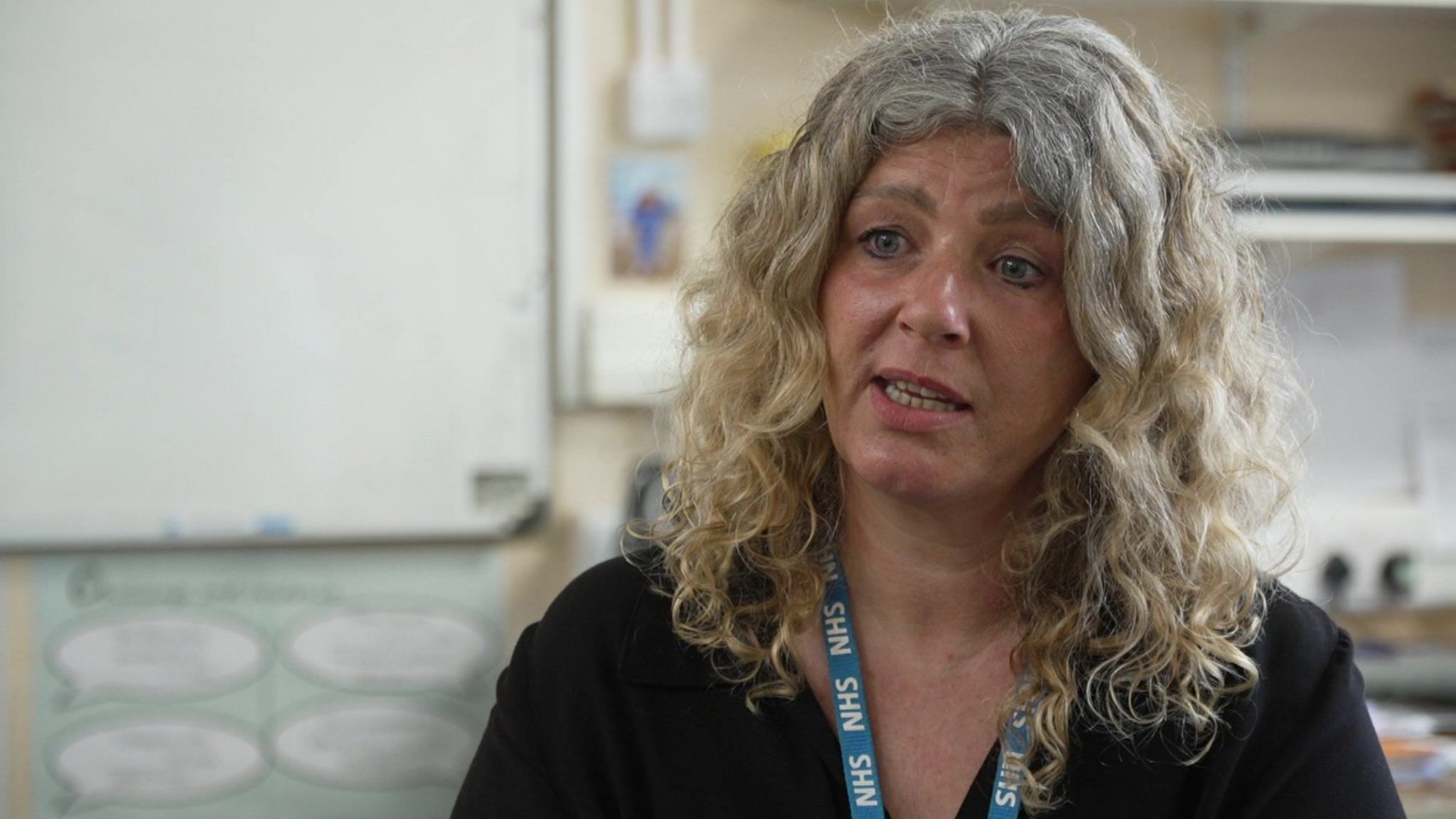 Woman with curly hair and NHS lanyard