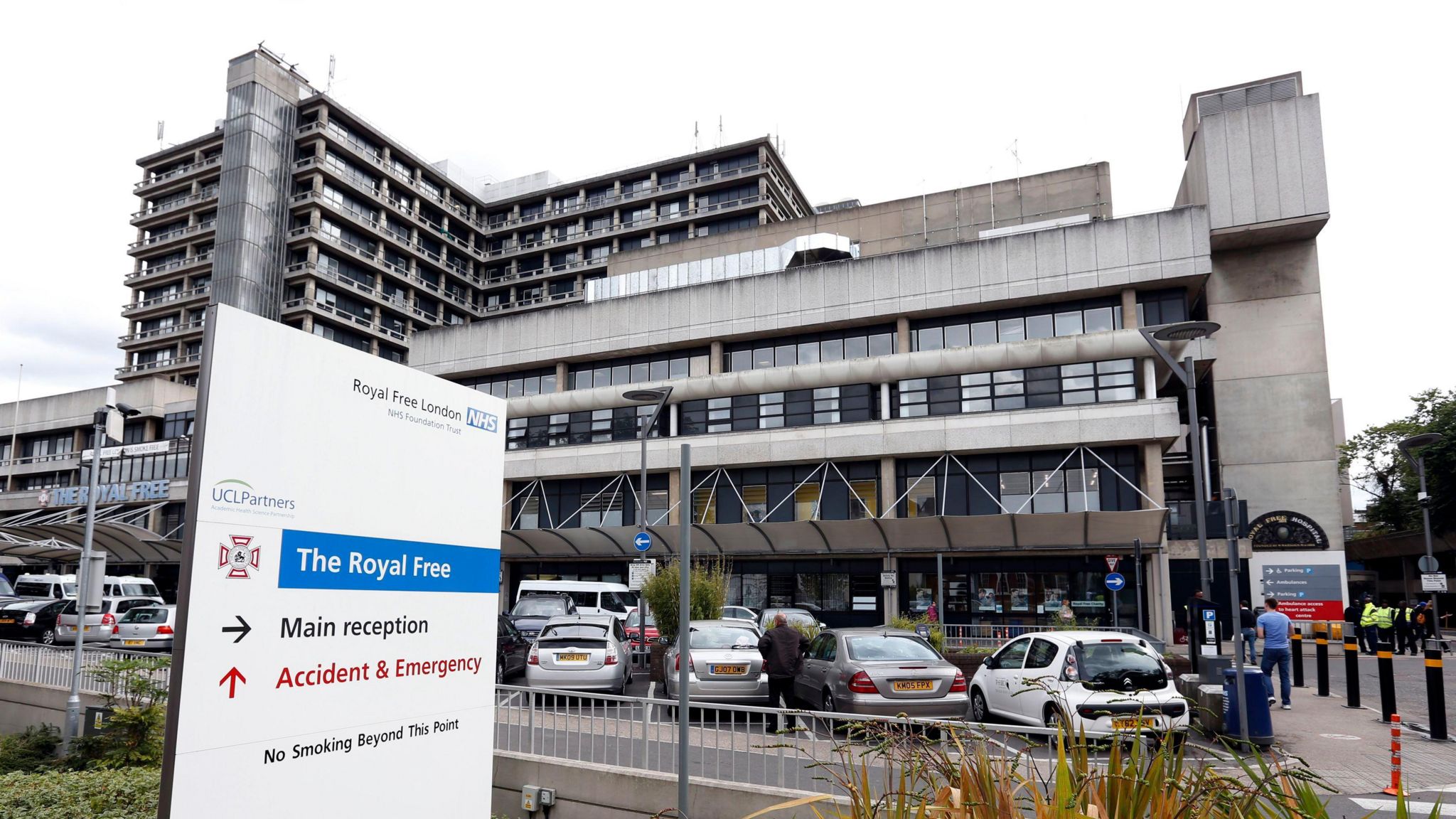 A general view of the exterior of the Royal Free Hospital, a concrete building with cars and a white and blue sign in front of it