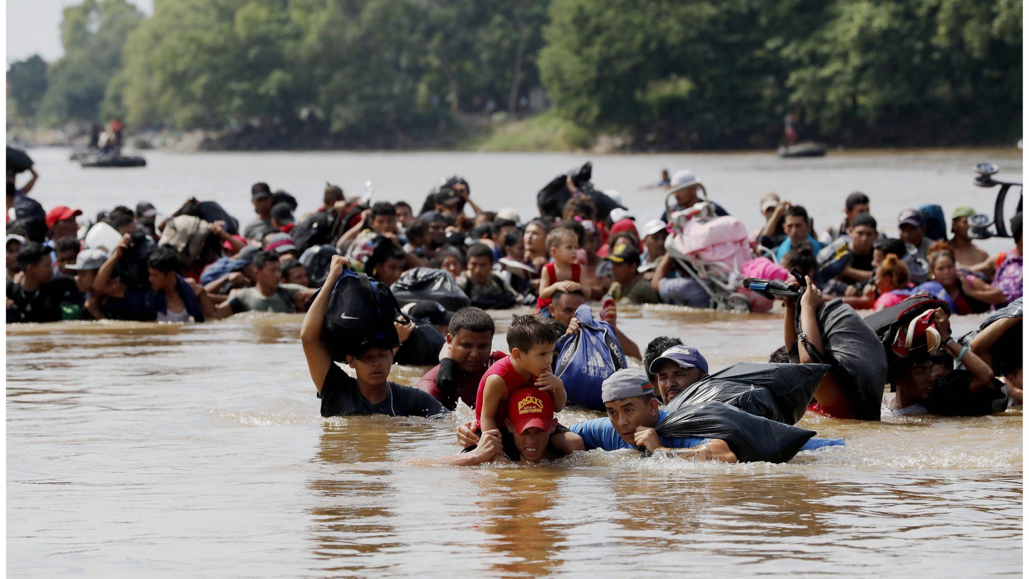 Migrants, mostly Hondurans, cross the Suchiate river, which separates Guatemala and Mexico, on 29 October 2018