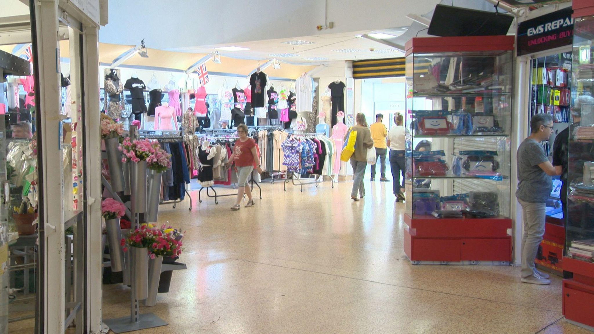 An image of market stalls at Ellesmere Port's central market. Flowers and rails of clothes are on display