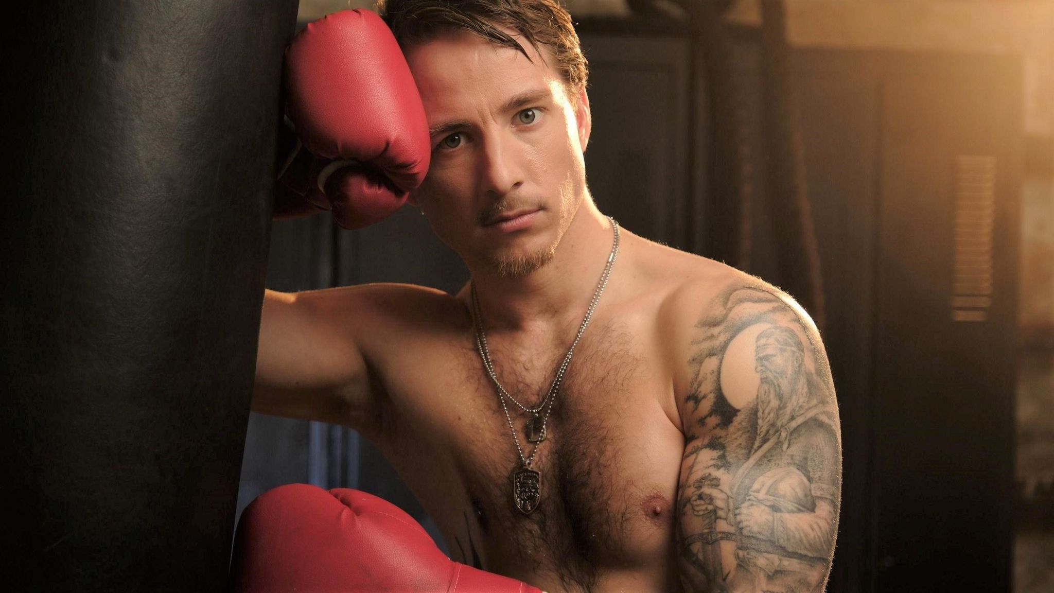 A shirtless man in boxing gloves