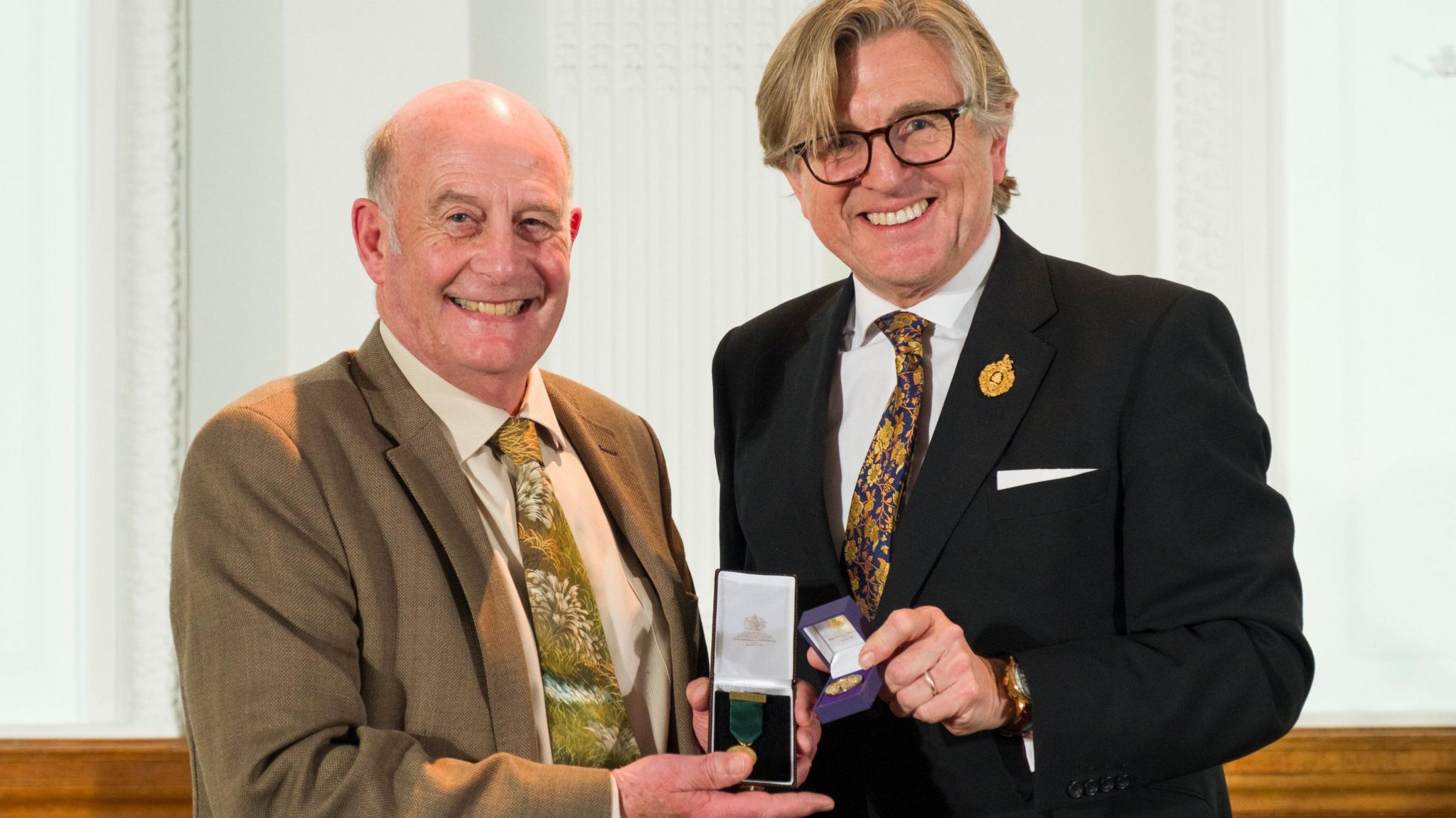 Neil Lucas (left) and Keith Weed holding the medal and smiling at the camera