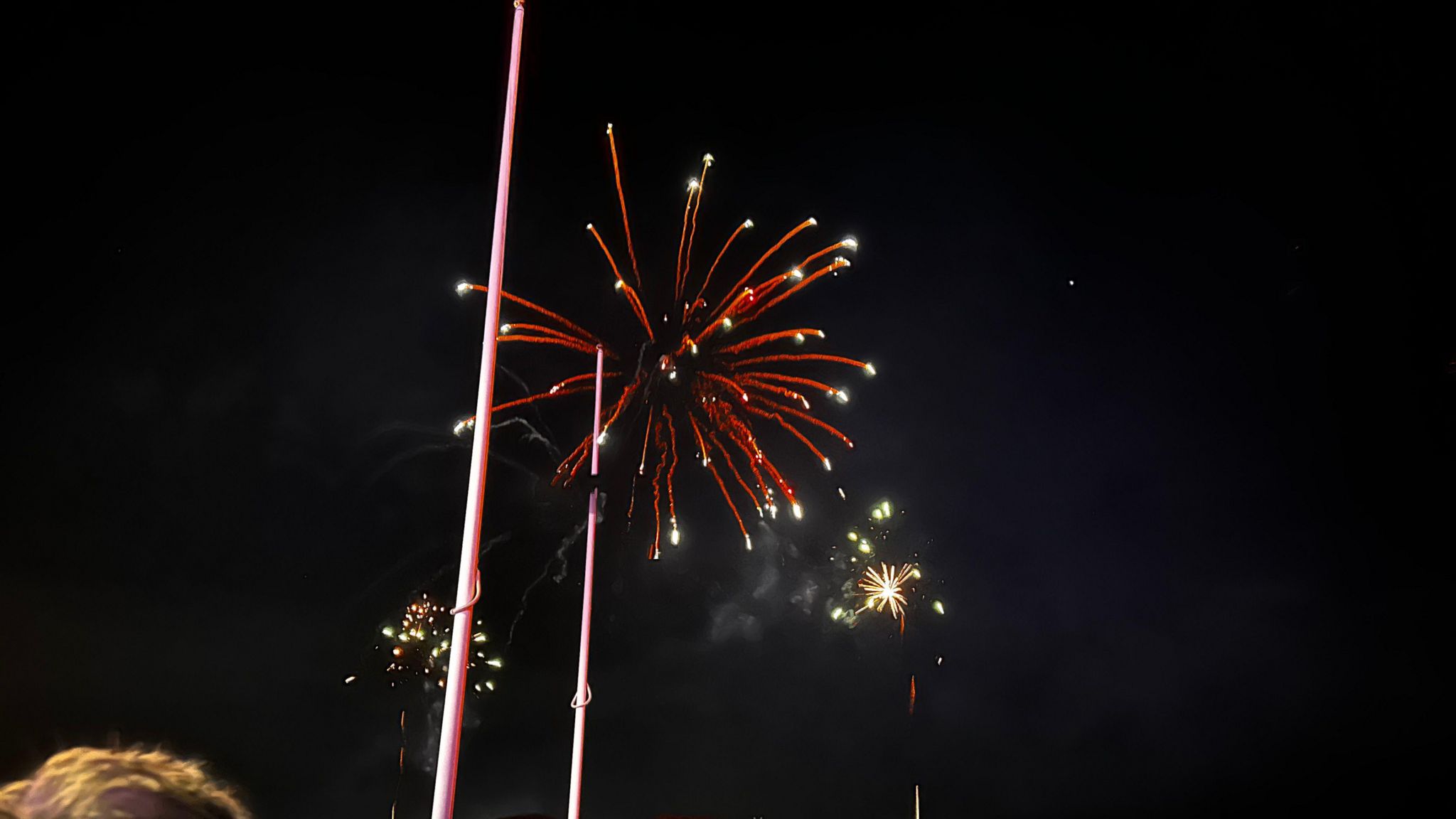 An orange firework explodes in the sky above Plymouth Hoe along with a couple of other pyrotechnics during the 2023 British Firework Championships