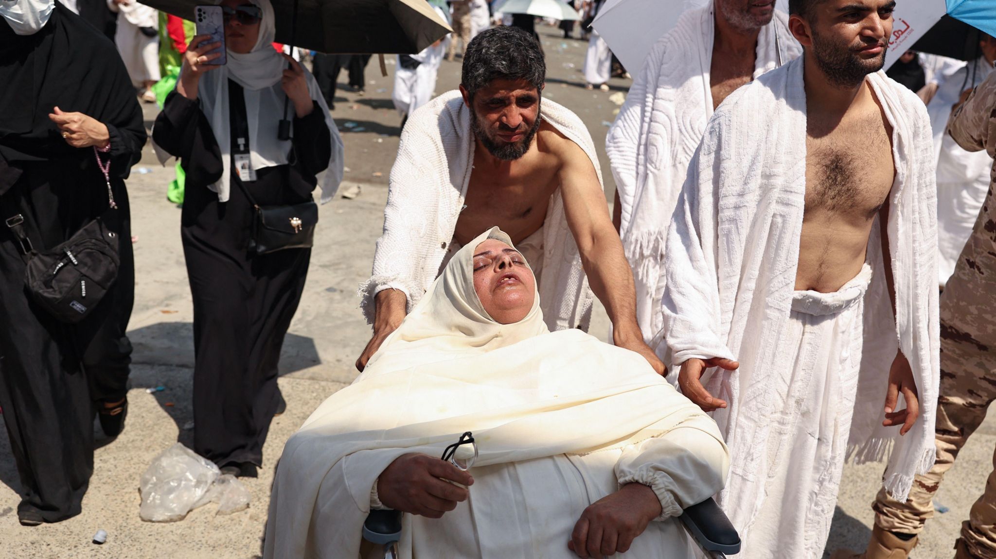 A woman affected by the scorching heat is pushed on a wheelchair as Muslim pilgrims arrive to perform the symbolic 'stoning of the devil' ritual as part of the hajj pilgrimage in Mina, near Saudi Arabia's holy city of Mecca, on June 16, 202