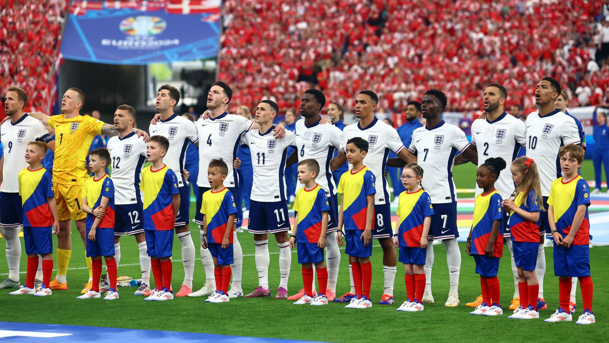 The England team sings the national anthem with the mascots in front of them