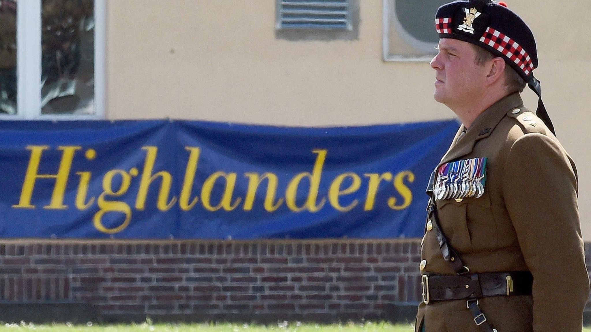 James Roddis in uniform with medals in front of a Highlanders regiment banner