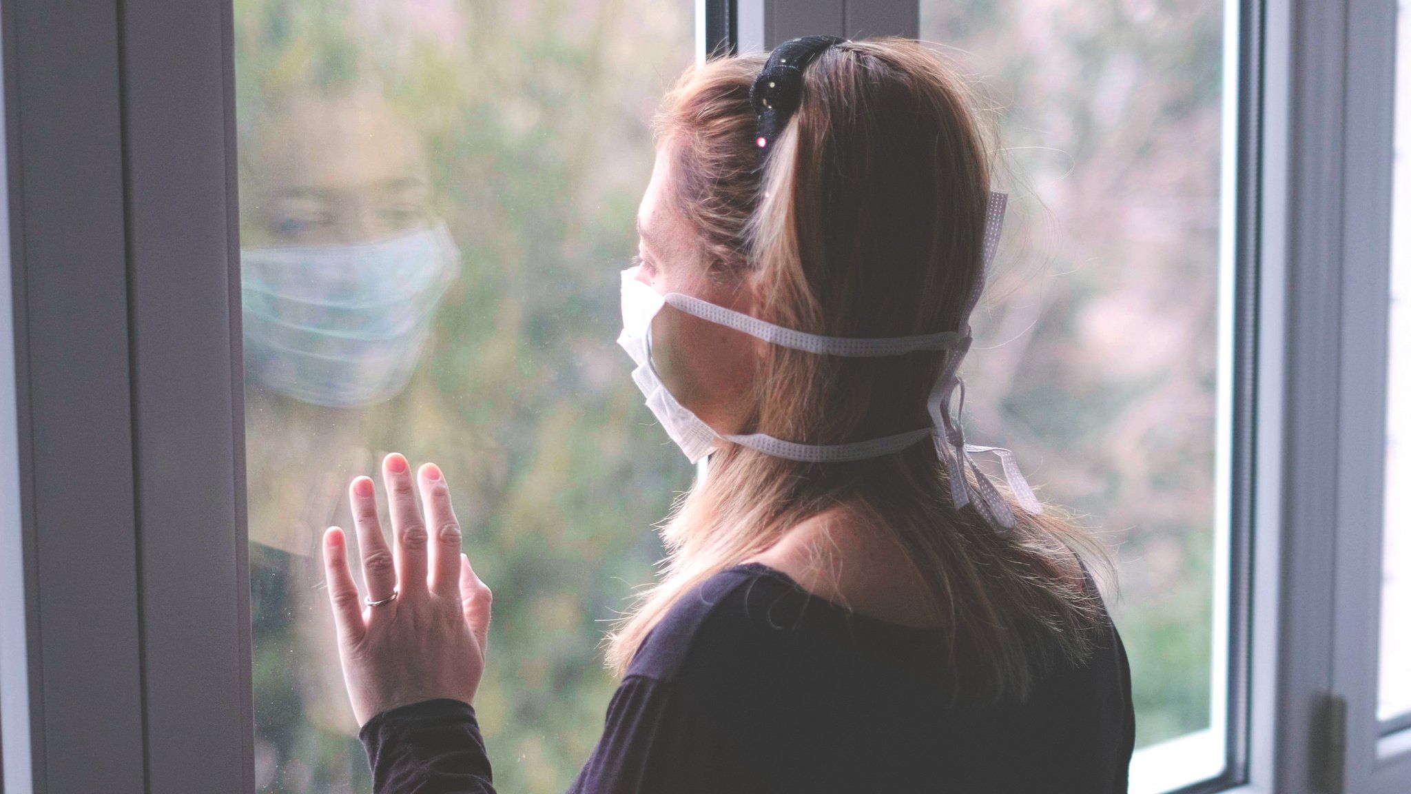 woman in mask looking out window