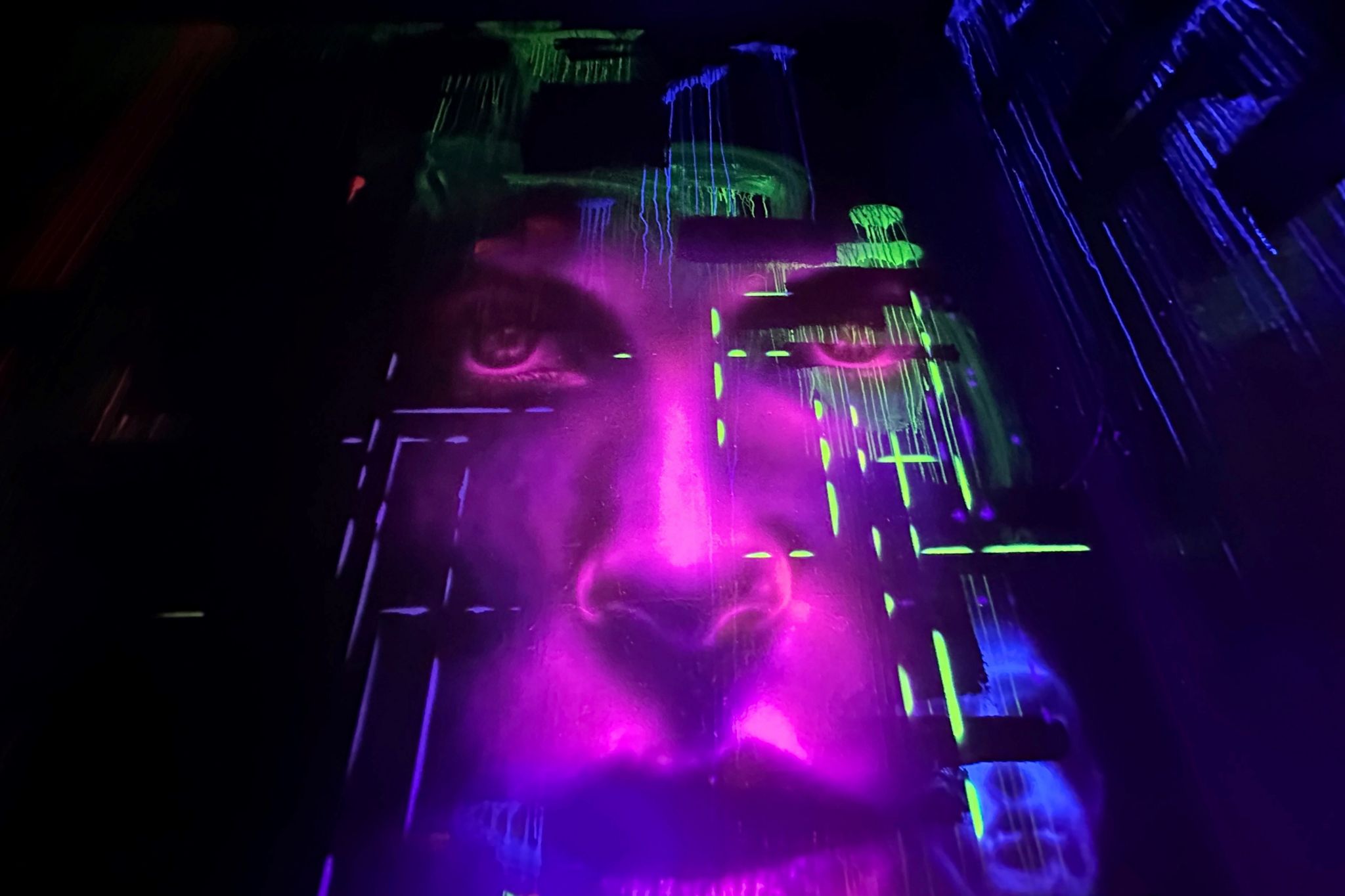 A neon mural of a purple face in the dark at the new Snobs