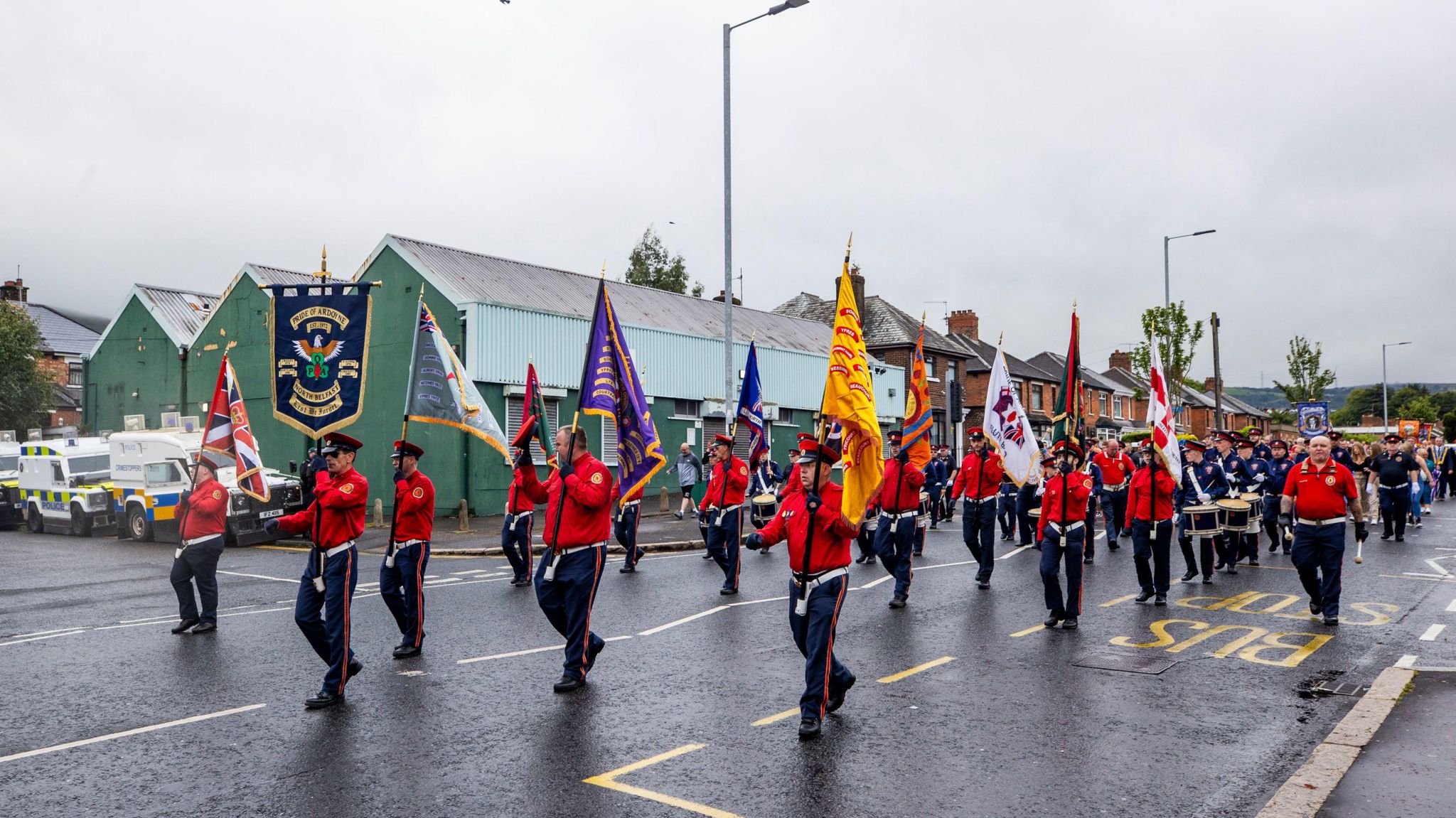 Men in red uniform carrying flags marching in a parade